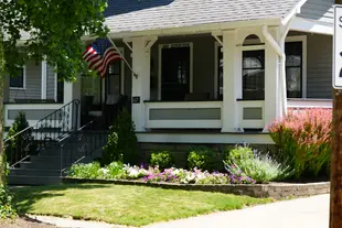 A traditional lawn with a front yard flower bed and american flag.