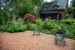 Brick base patio with metal deck chairs in front of a large native, green garden at someones home
