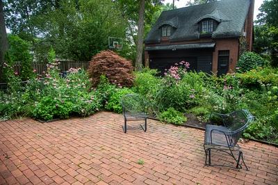 Brick base patio with metal deck chairs in front of a large native, green garden at someones home
