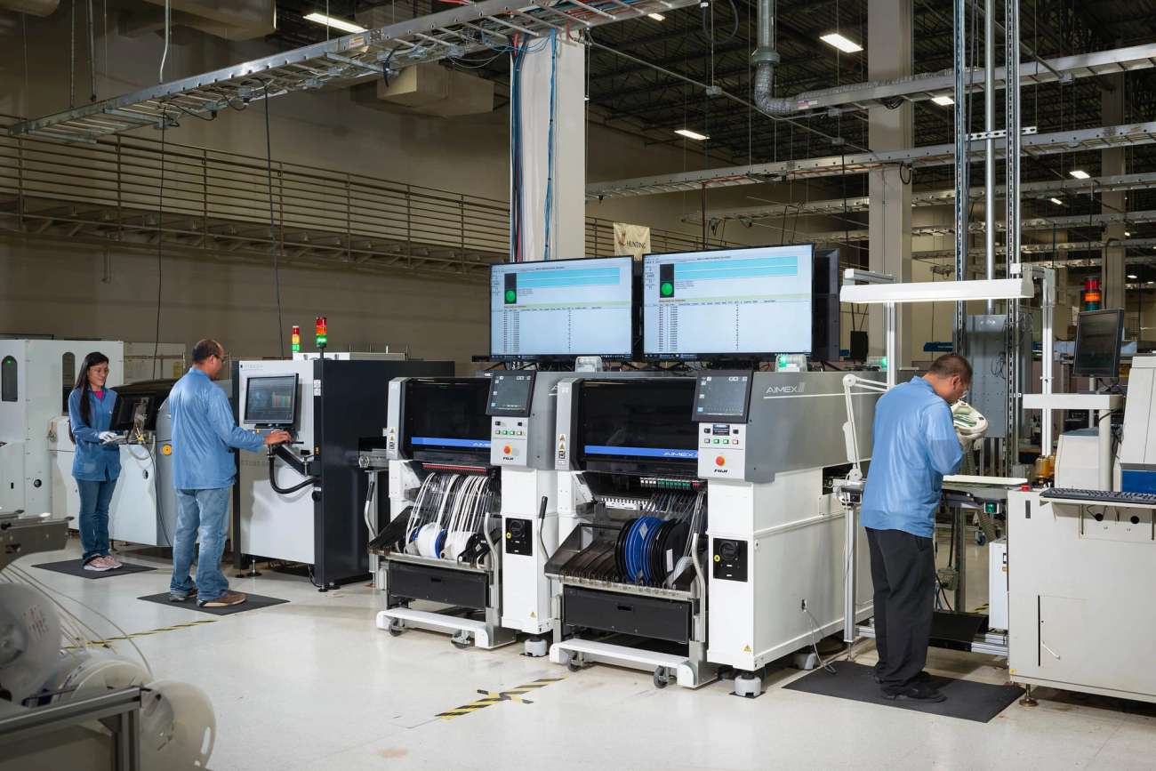Manufacturing facility with 3 people in blue coats working on machines