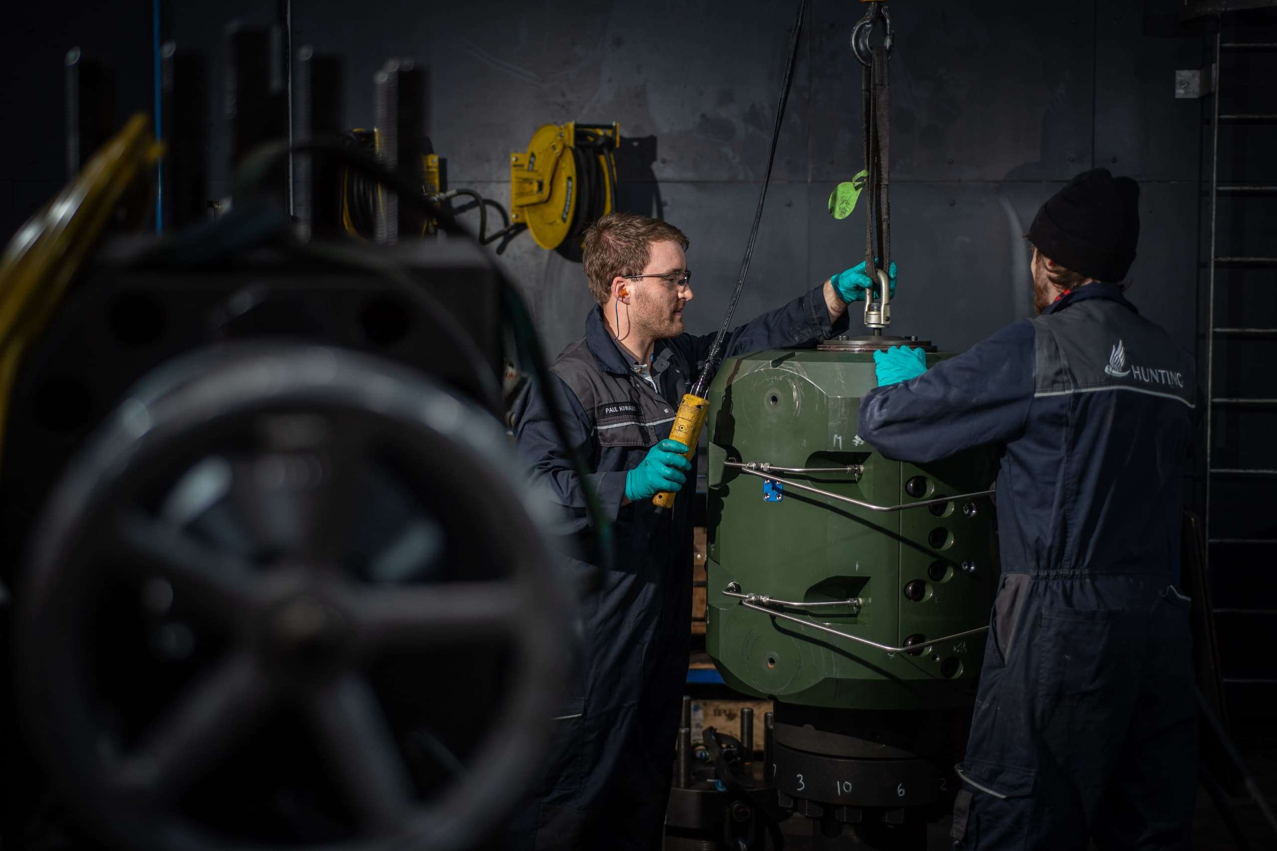 Two Hunting employees in boiler suits tend machinery