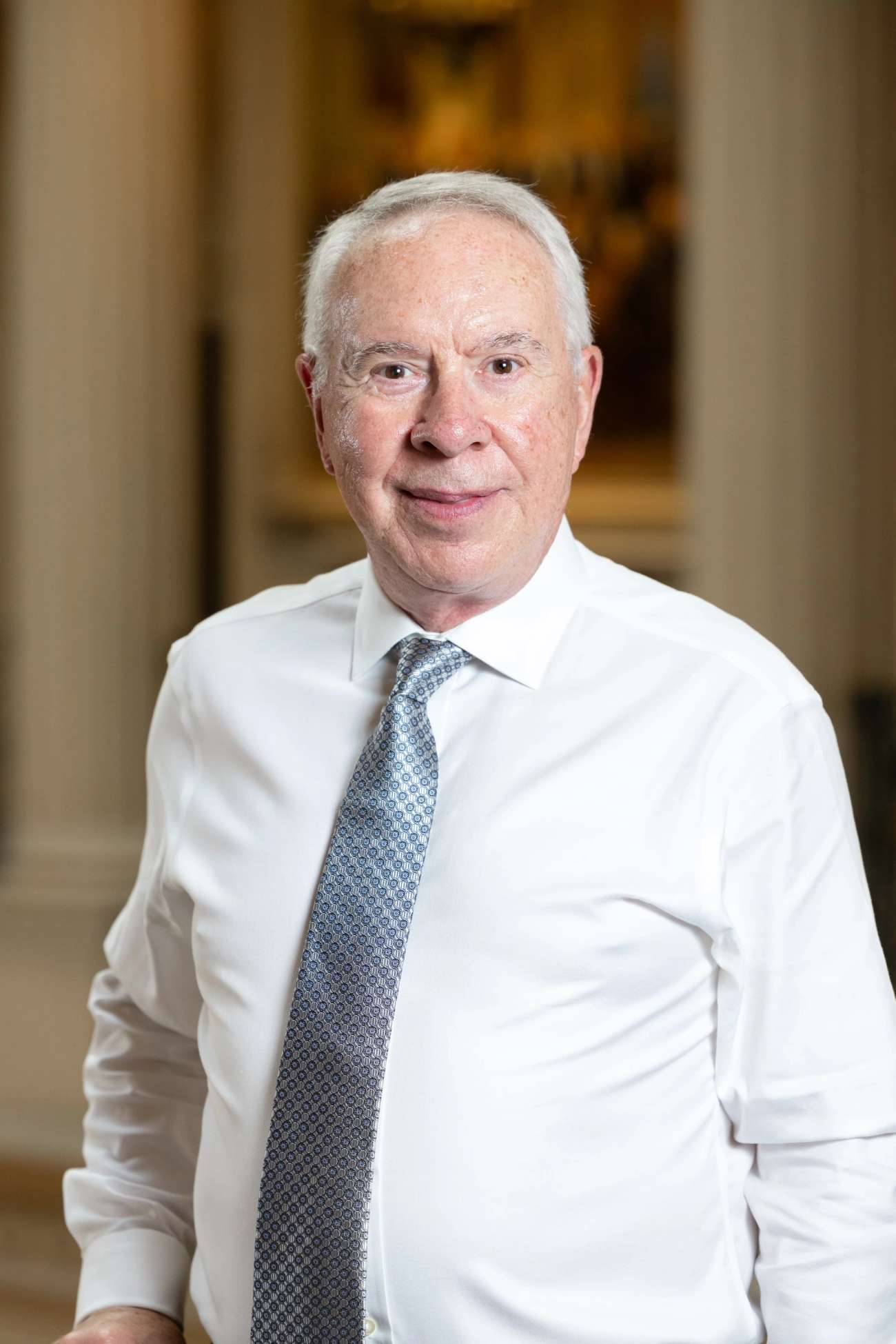 White male with short grey hair in white shirt and tie looking in camera