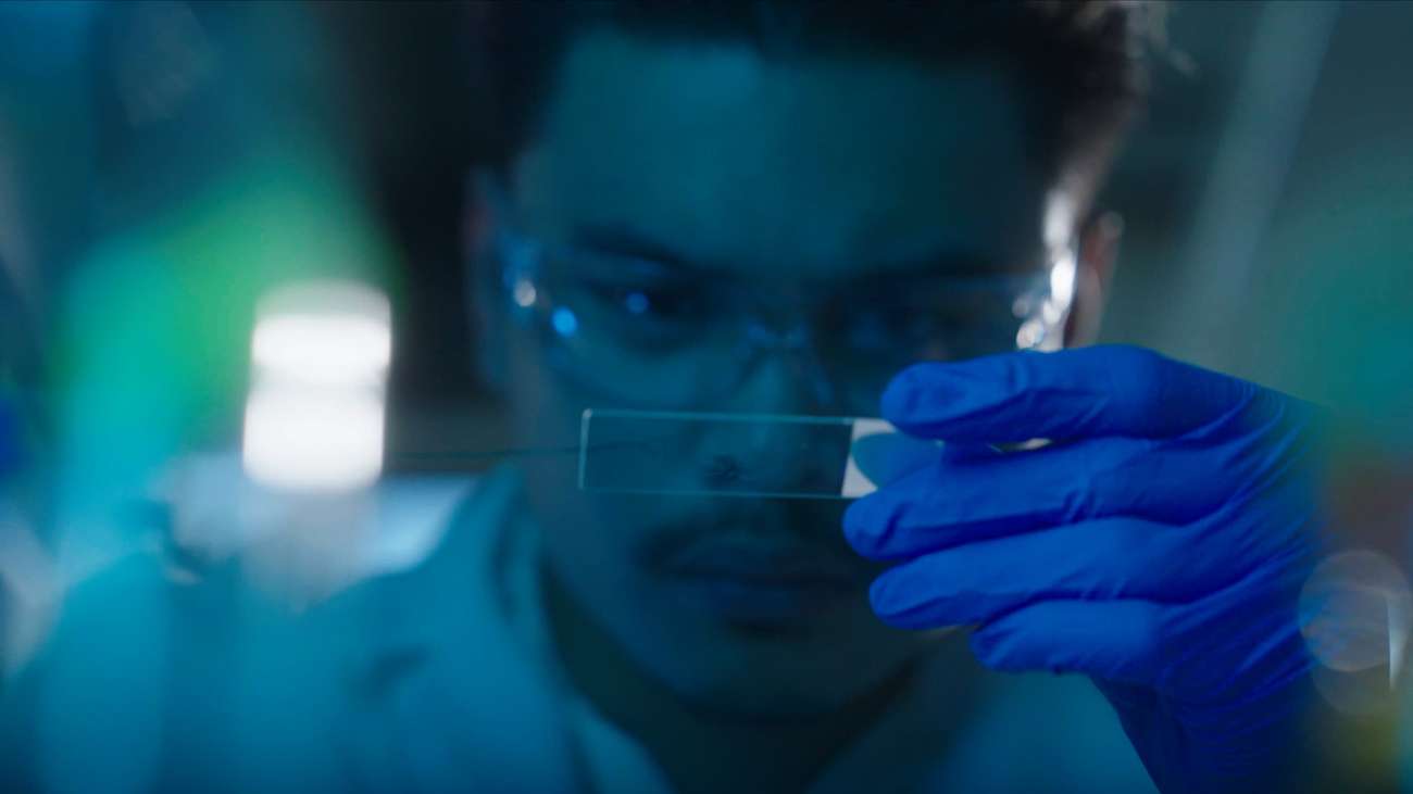 man in lab looking at microbe sample
