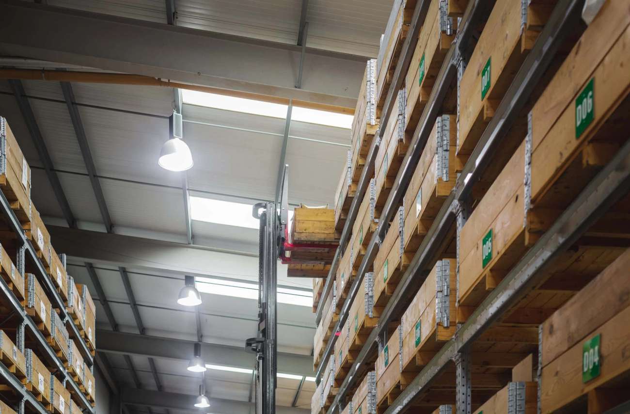 Shelves in warehouse with wooden boxes and a forklift