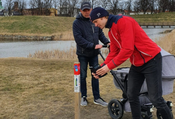 To menn med barnevogn scanner kode på stolpe