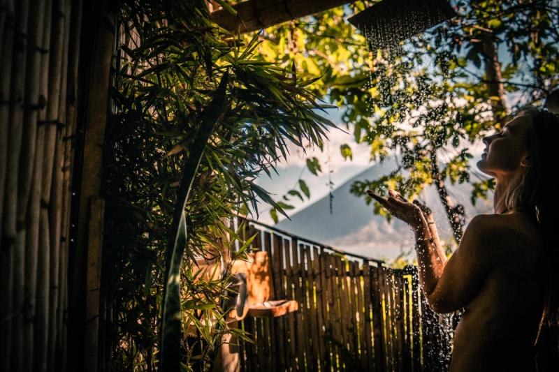 Outdoor shower lifestyle shot, golden hour sunlight and volcano in background