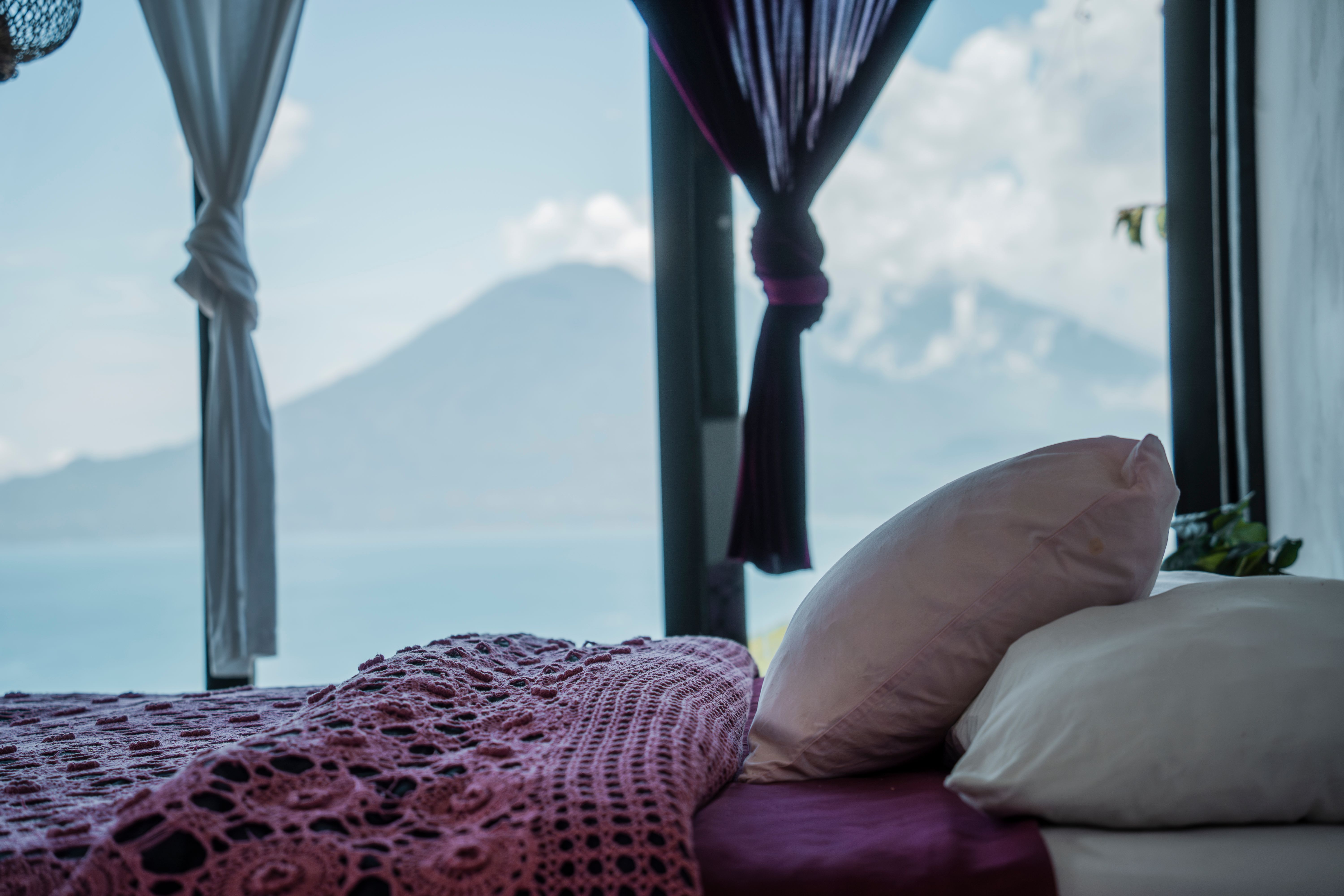 Aves Silvestres suite at Eagle's Nest Atitlan, pillows with Lake Atitlan volcano view through gauzy curtains