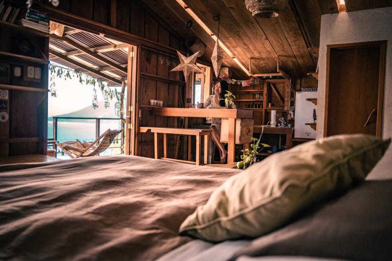 Privates Zimmer mit eigenem Bad, Holzwänden und Patchwork-Steppdecke, warmes goldenes Licht