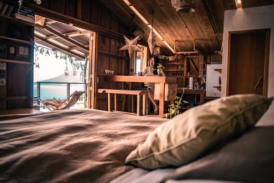 Privates Zimmer mit eigenem Bad, Holzwänden und Patchwork-Steppdecke, warmes goldenes Licht