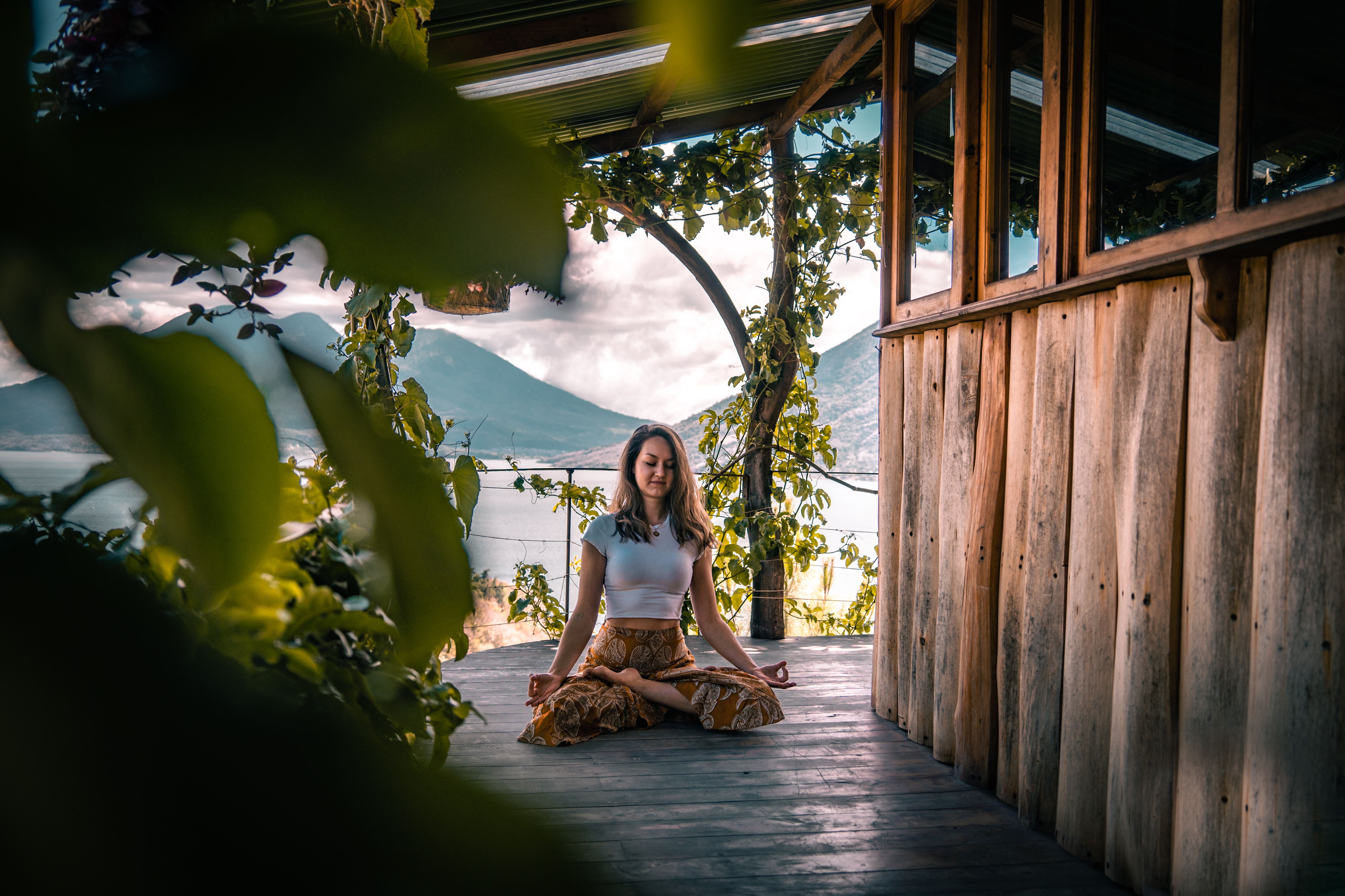 Mujer en postura de meditación del loto, con un volcán y un lago al fondo