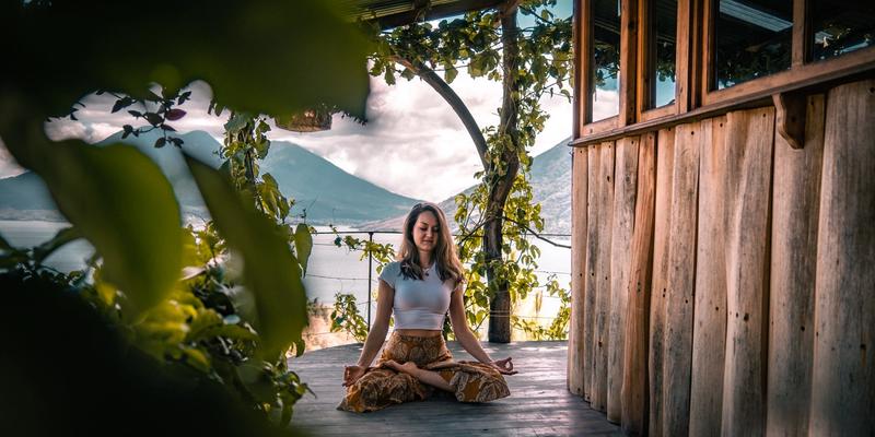 Mujer en postura de meditación del loto, con un volcán y un lago al fondo