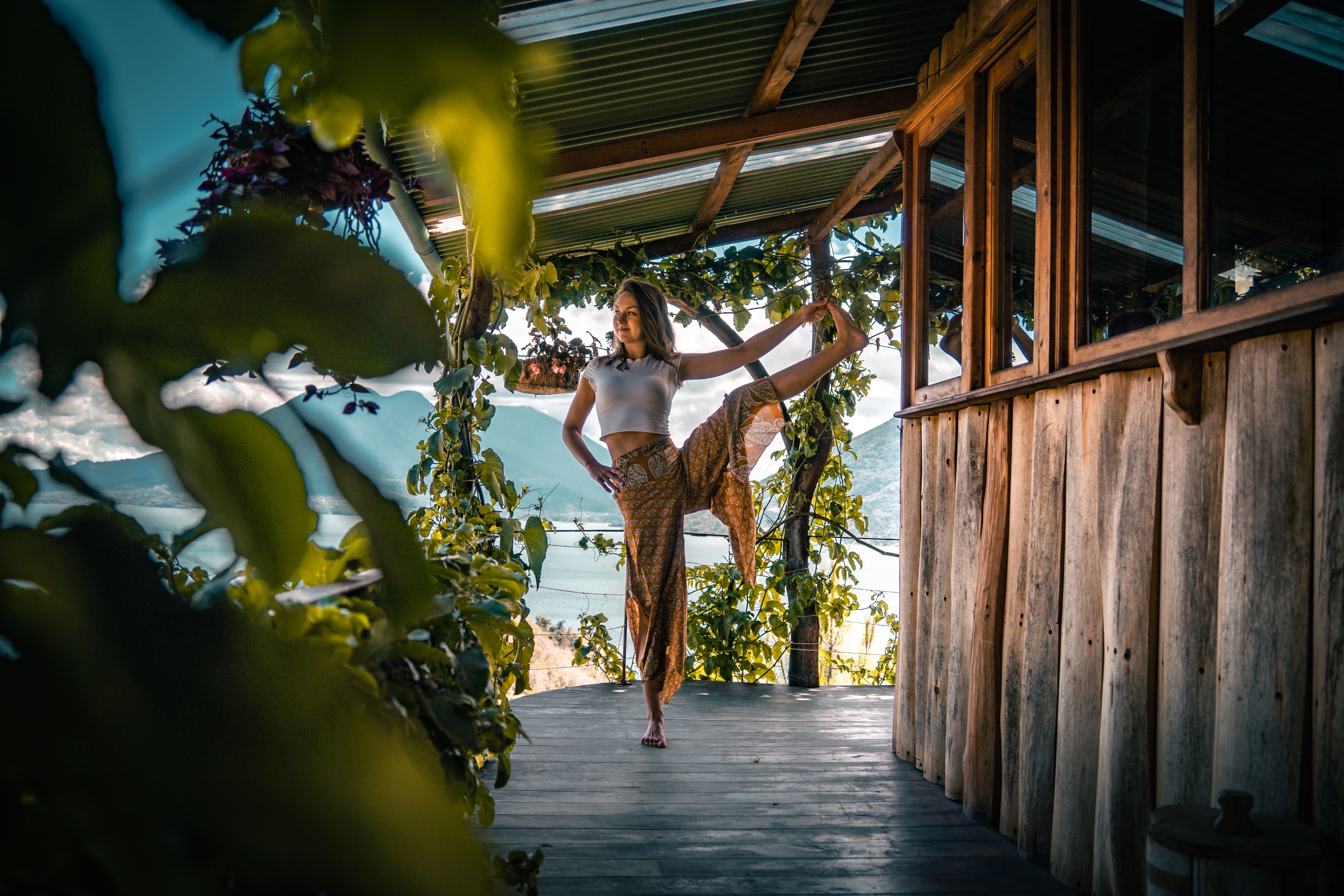 Mujer realizando la postura de yoga de la apertura de piernas de pie con vistas al volcán