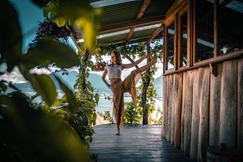 Frau, die auf der Terrasse eine Balance-Pose im stehenden Spagat ausführt