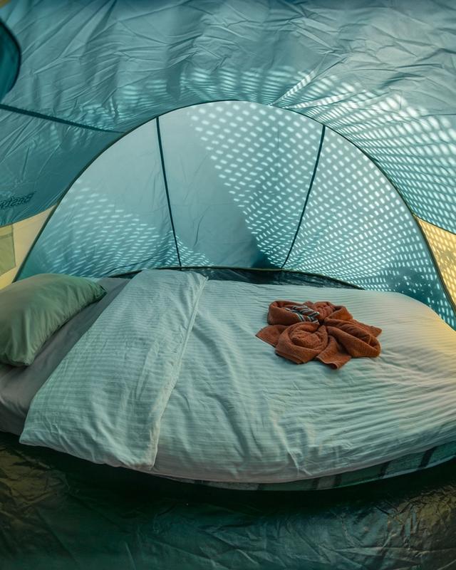 Comfortable tent interior with real mattress, bedding and rolled towels