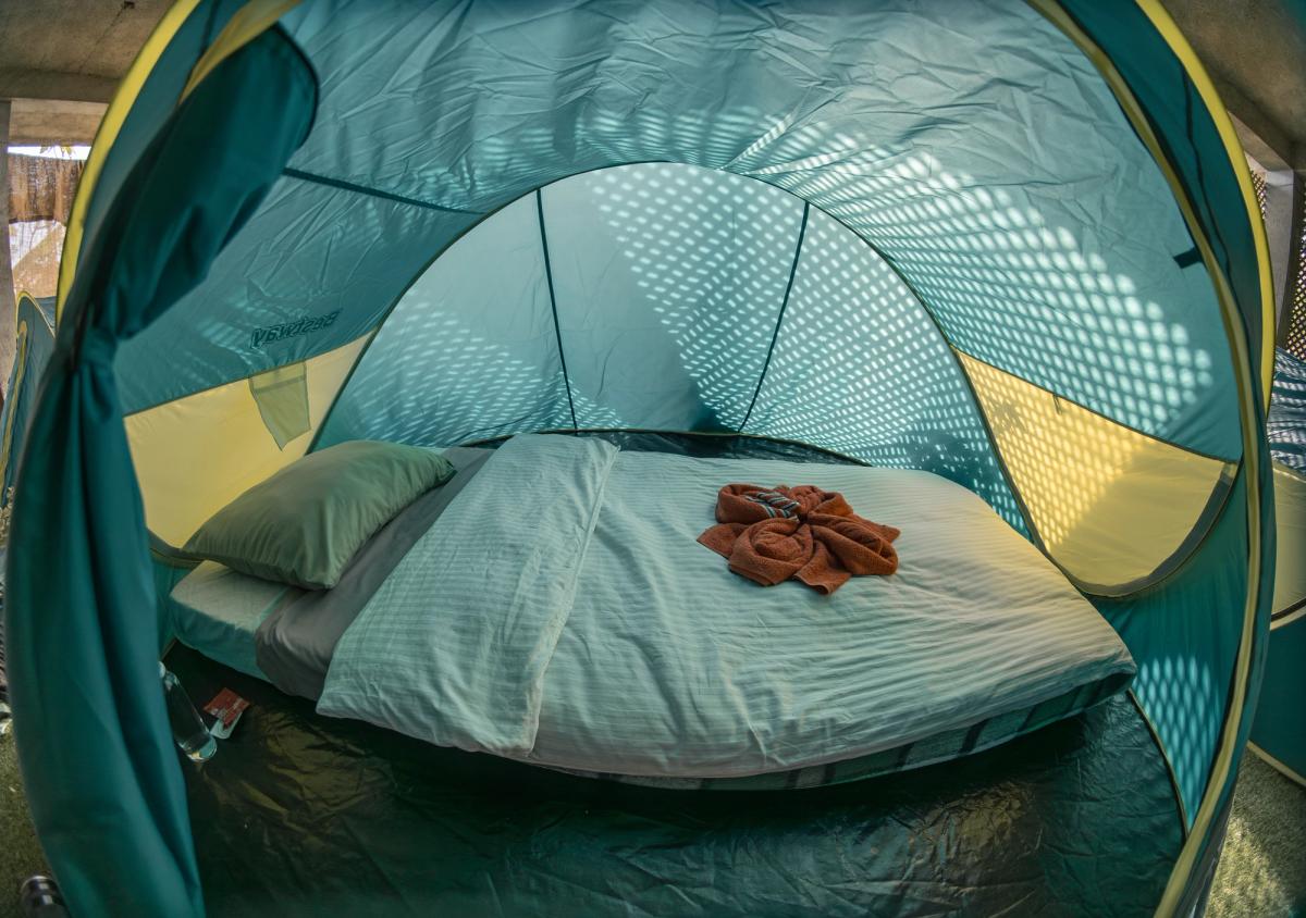 Comfortable tent interior with real mattress, bedding and rolled towels