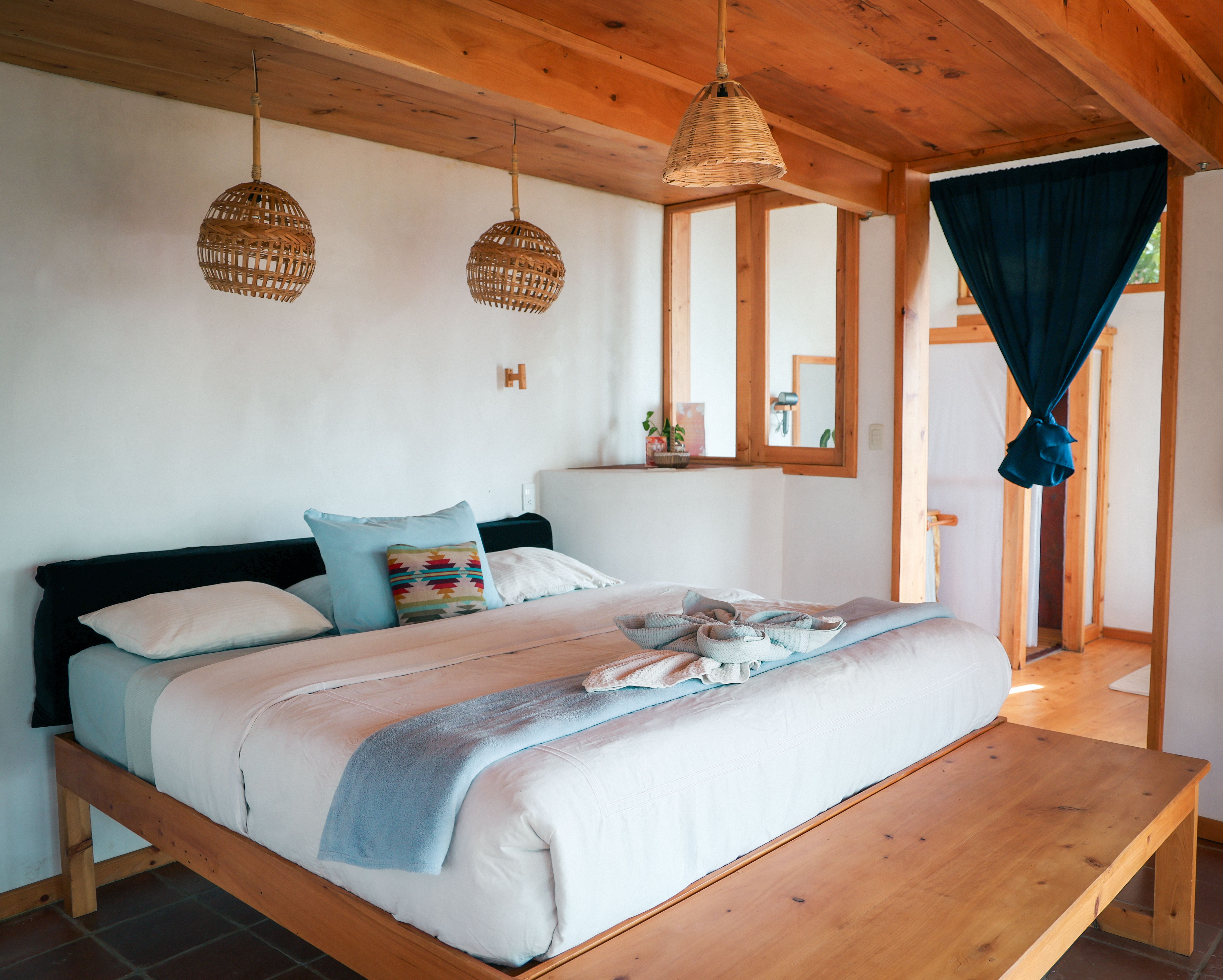 Rey suite bedroom with framed bed, rattan pendant lamps and welcome detail