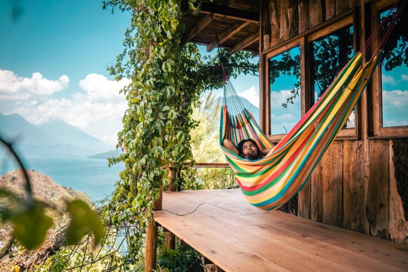 Person in einer Hängematte auf einer Terrasse mit Blick auf einen See und einen Vulkan