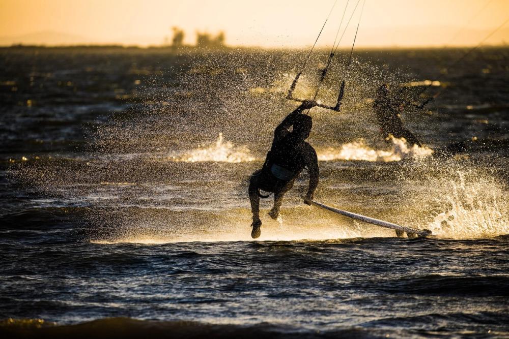 Kiteboarder silhouetted in golden spray at sunset