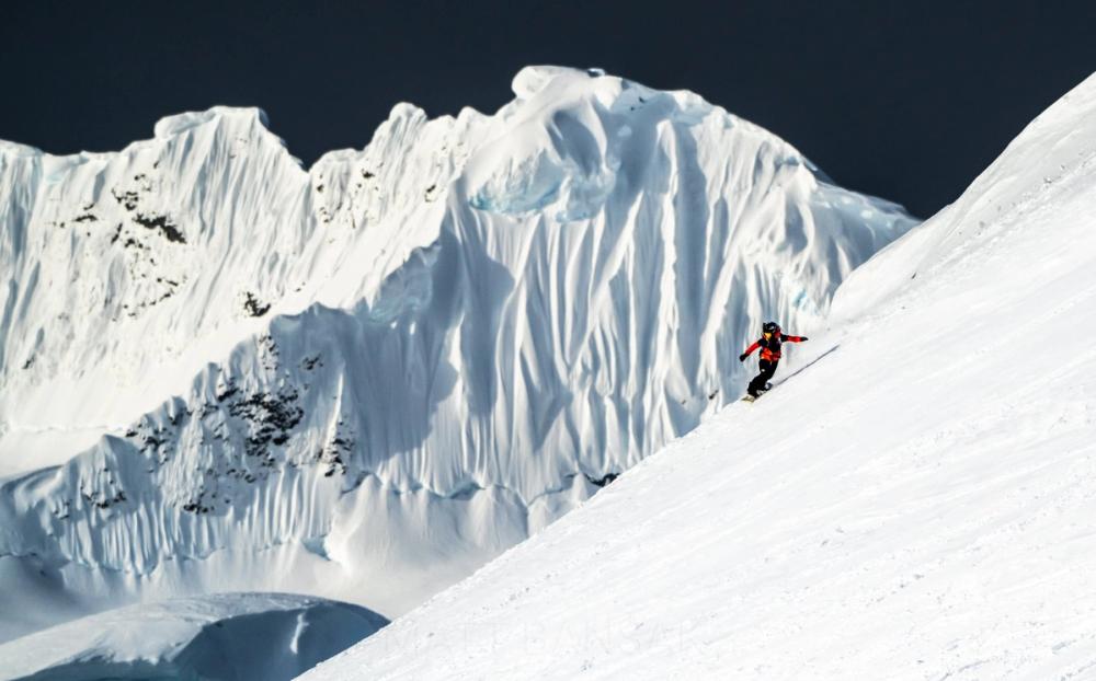 Skier below towering ice cliffs in Antarctica
