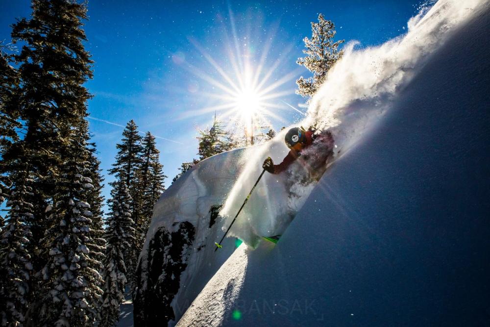 Skier throwing a powder spray under a sunburst