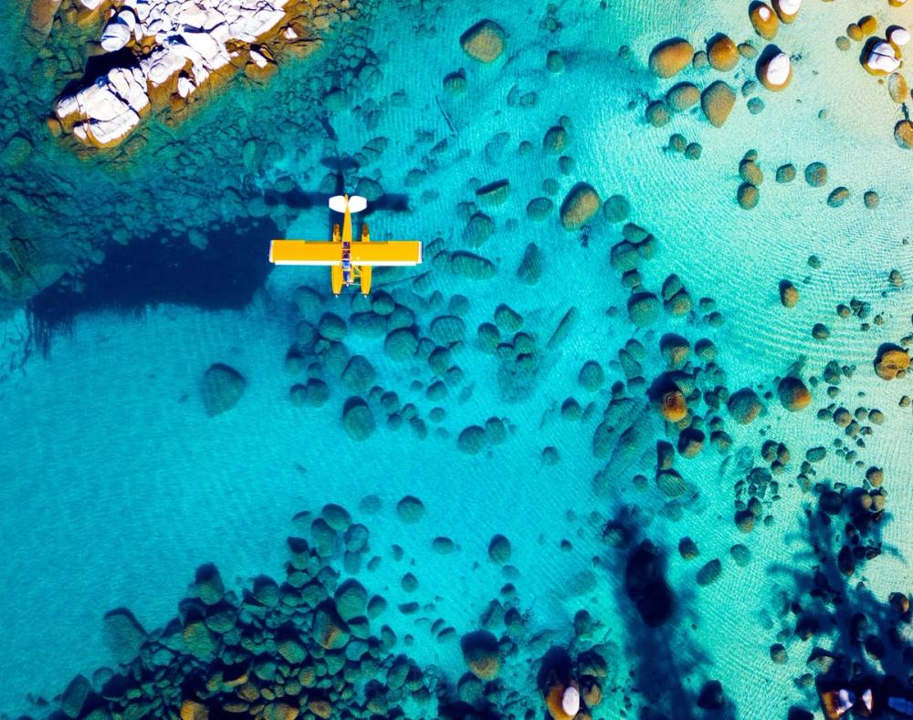 Aerial of a yellow floatplane over turquoise Lake Tahoe water
