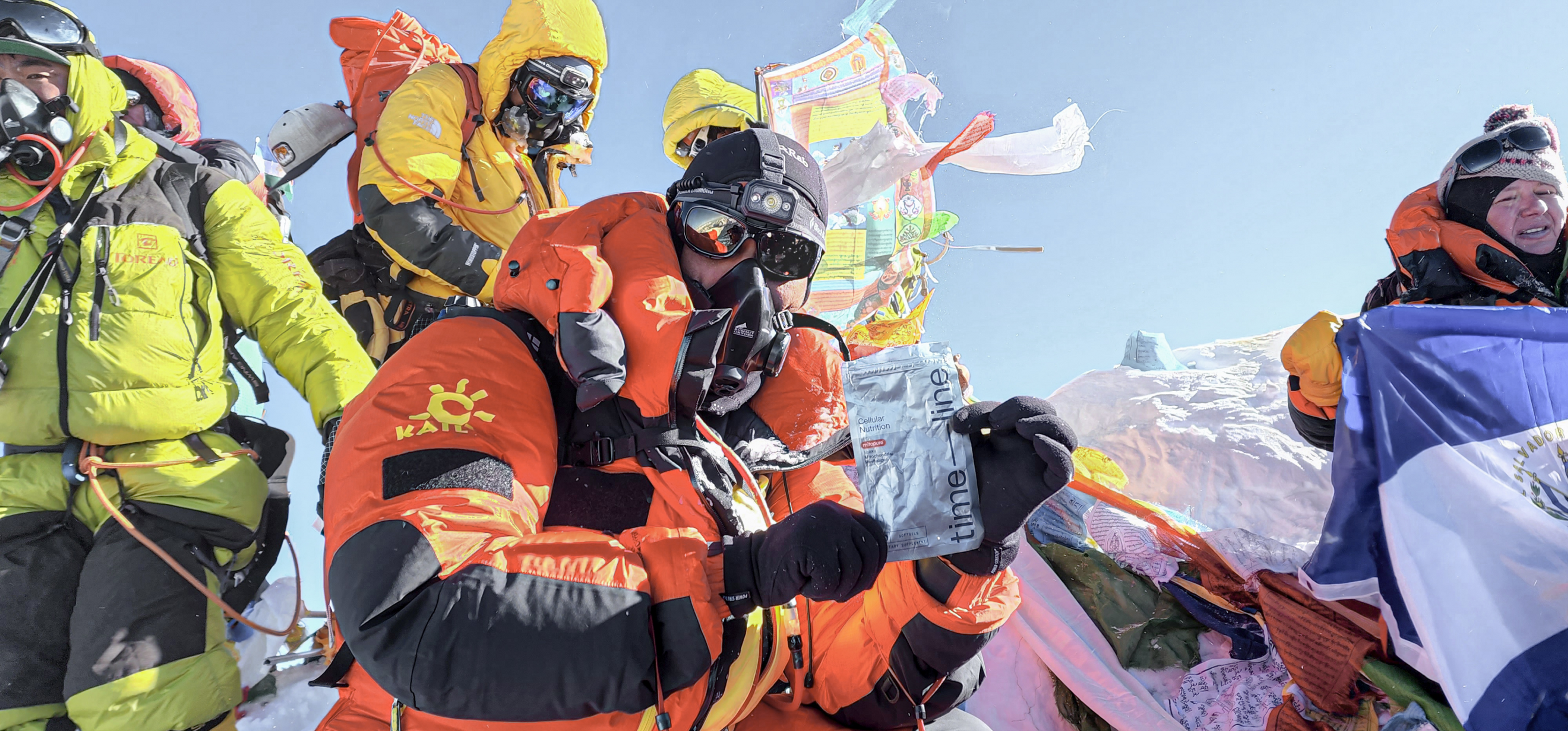 Jatin on top of Mt. Everest holding a pack of Timeline's Mitopure Softgels