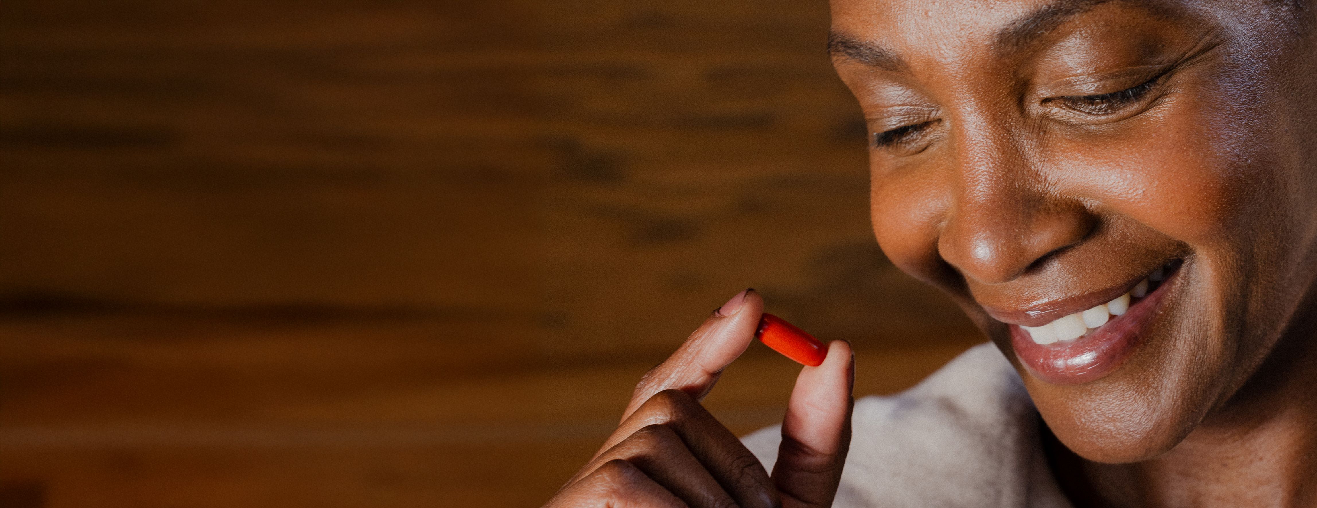 Smiling woman holding a Urolithin A Mitopure Softgel