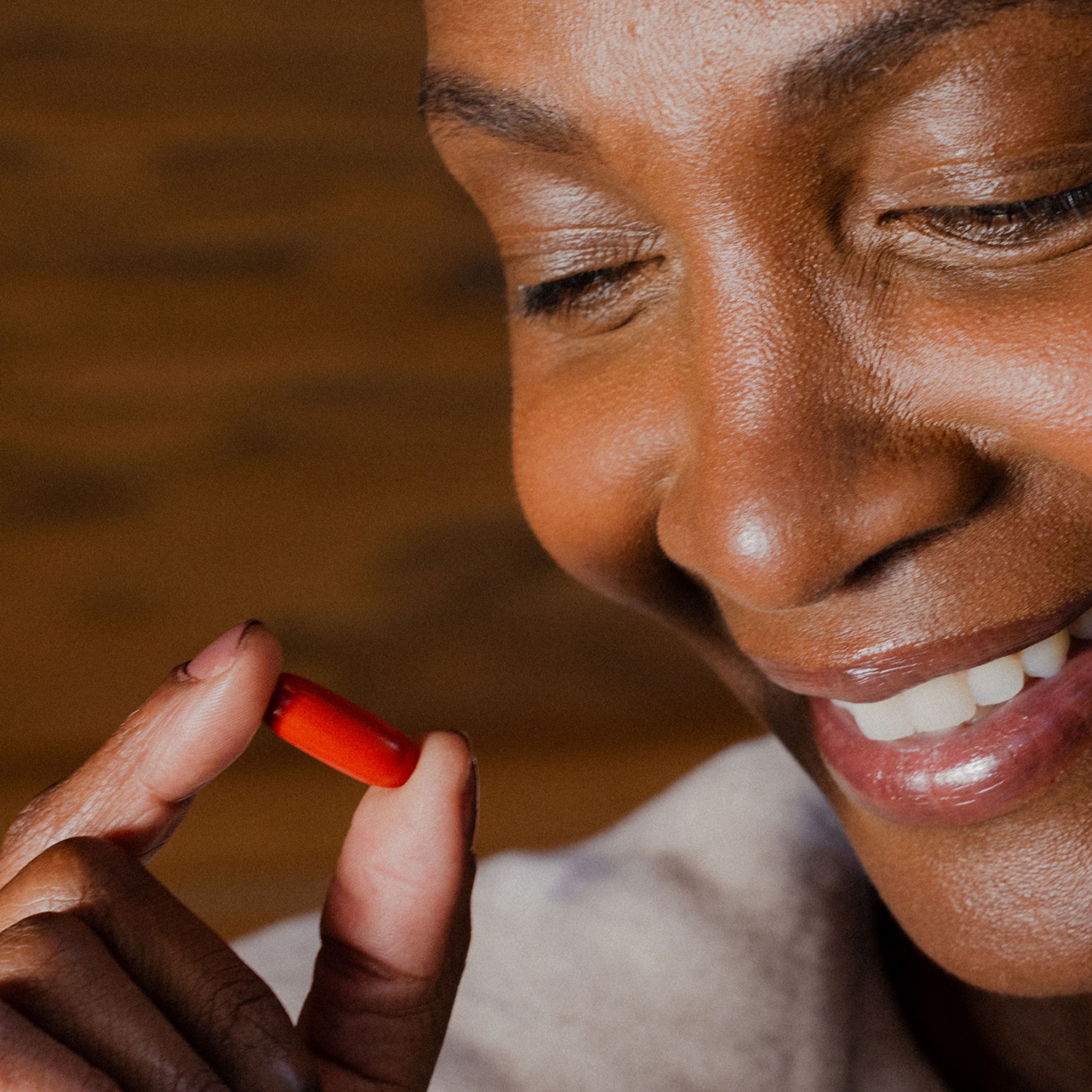 Smiling woman holding a Urolithin A Mitopure Softgel