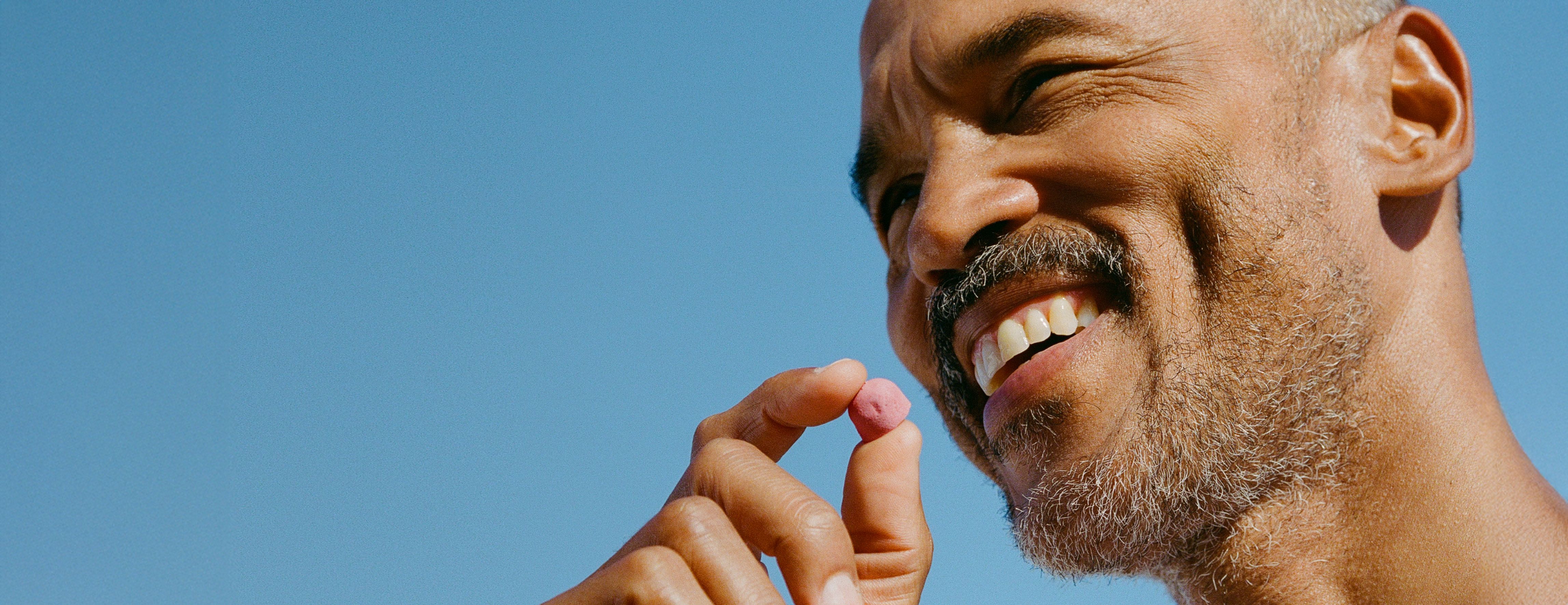 Smiling man holding a Urolithin A Mitopure Gummy