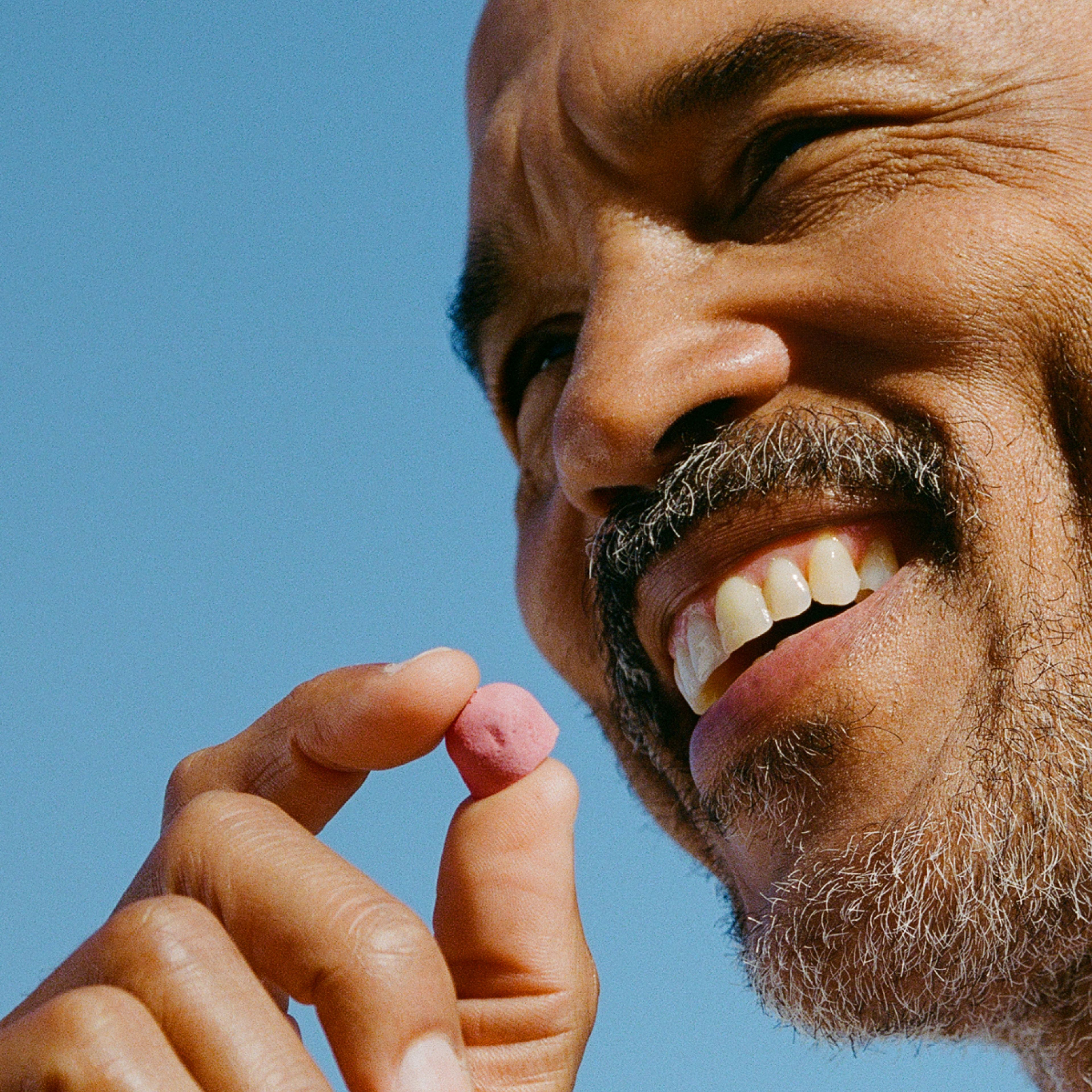 Smiling man holding a Urolithin A Mitopure Gummy