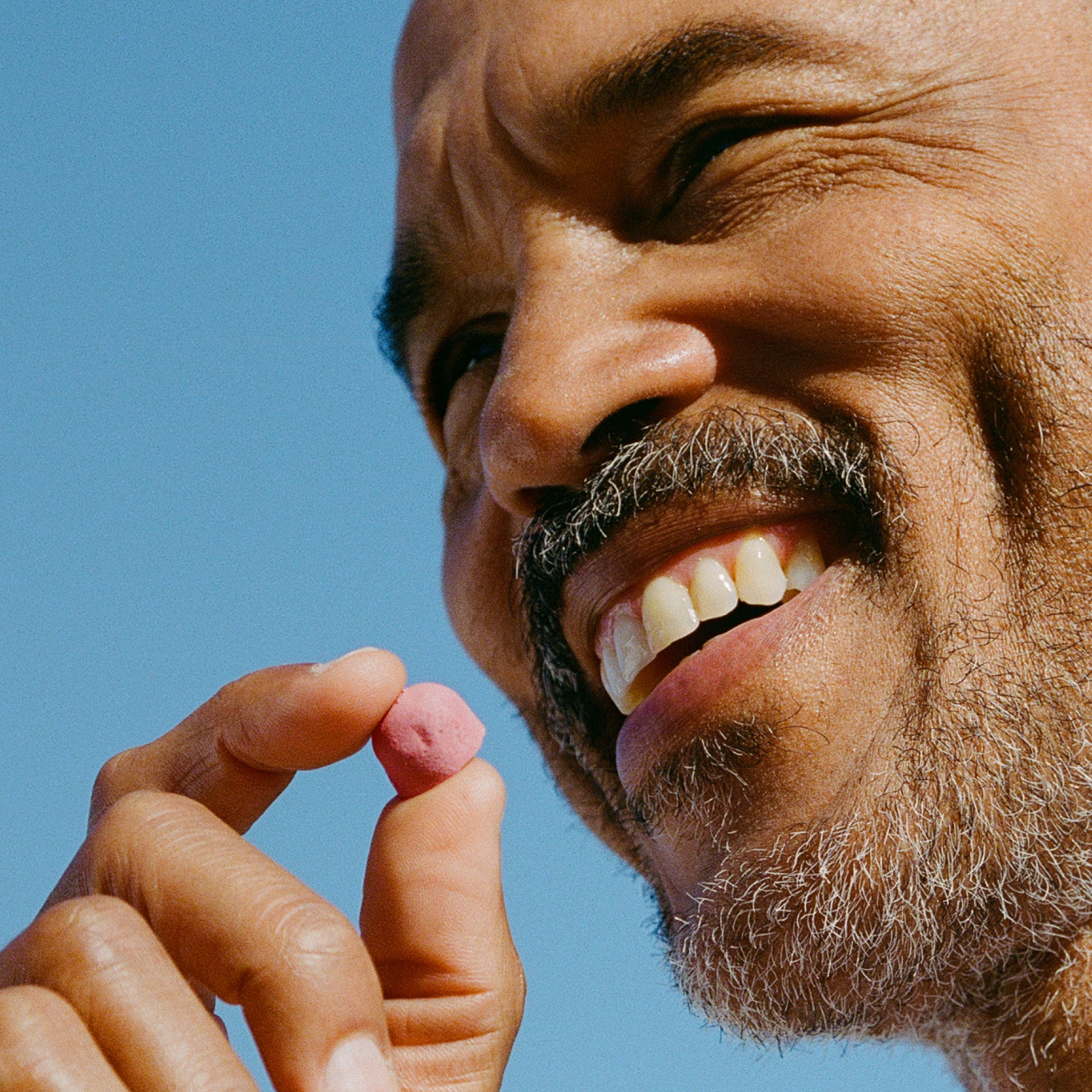 Smiling man holding a Urolithin A Mitopure Gummy