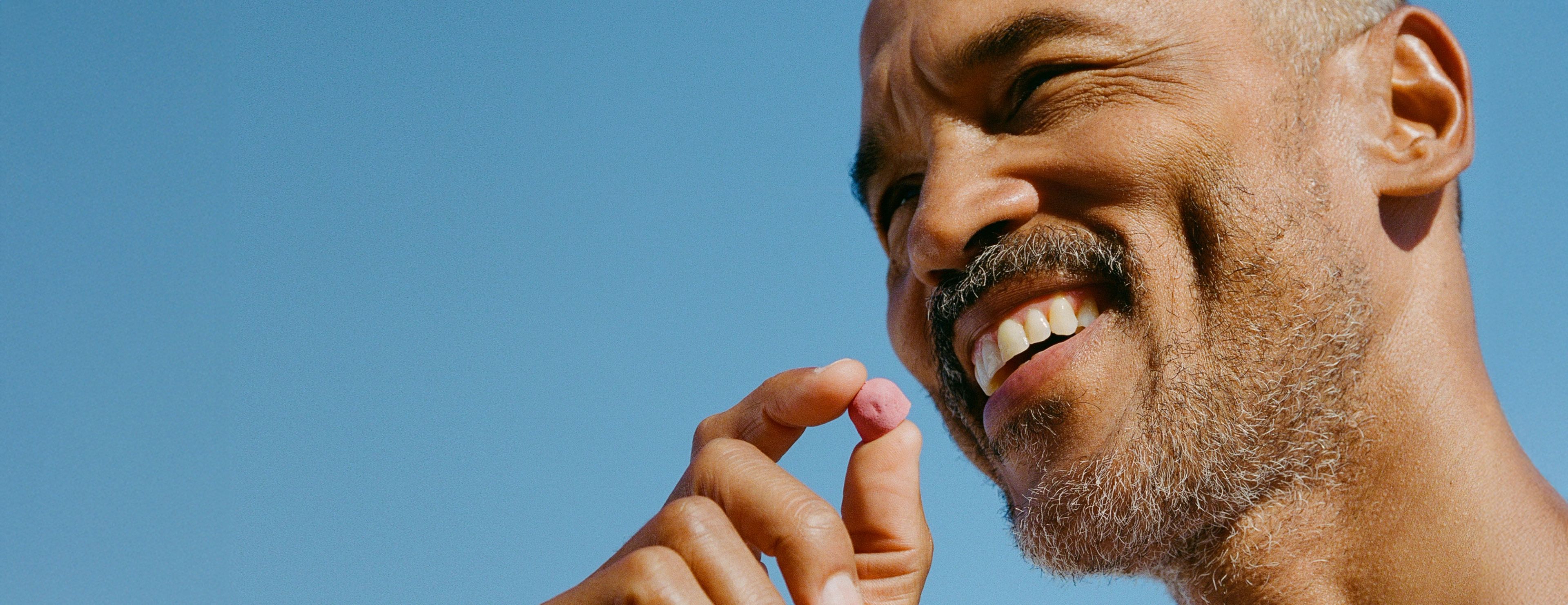 Smiling man holding a Urolithin A Mitopure Gummy