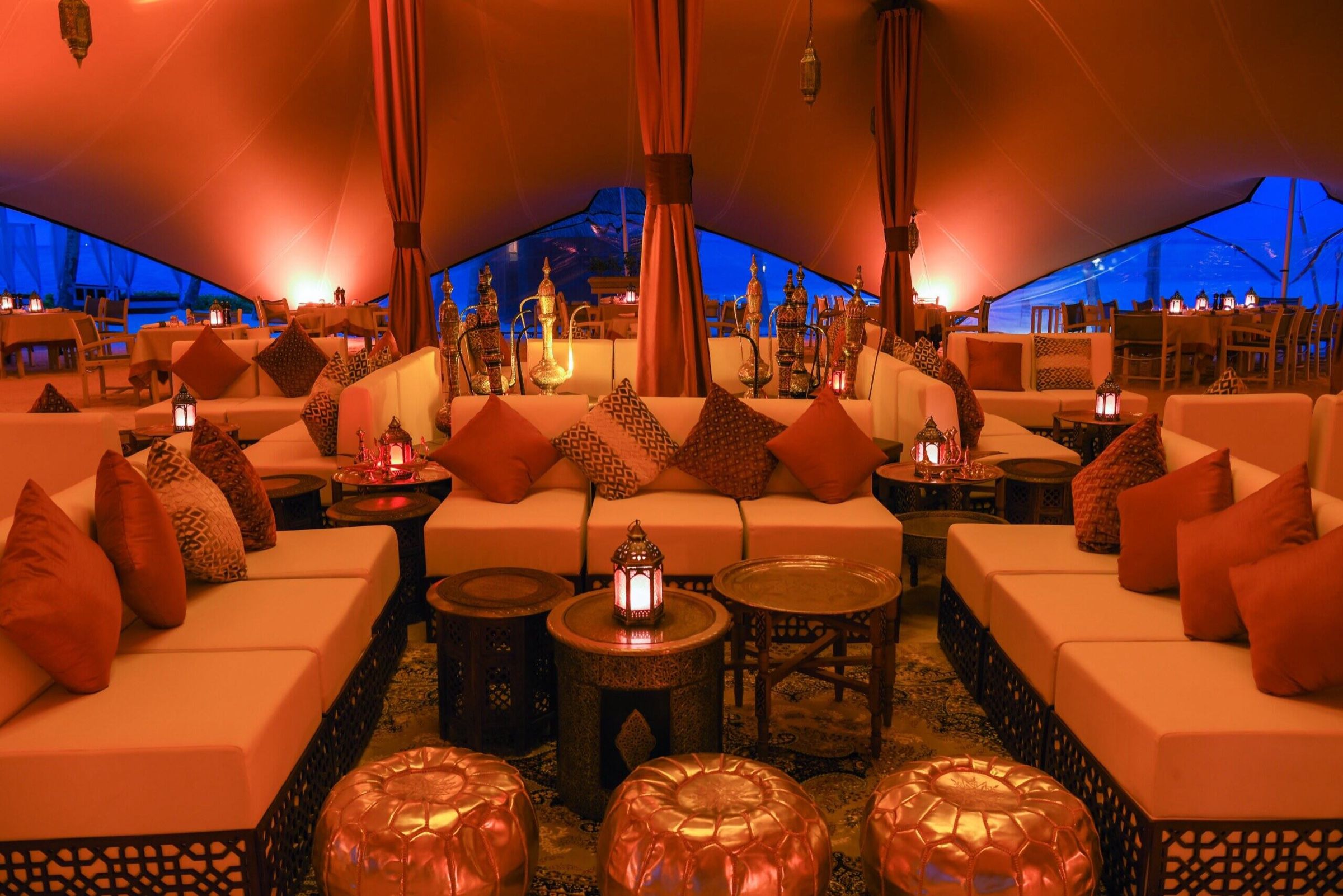 Arabian lounge with orange cushions and brass lanterns under a tent