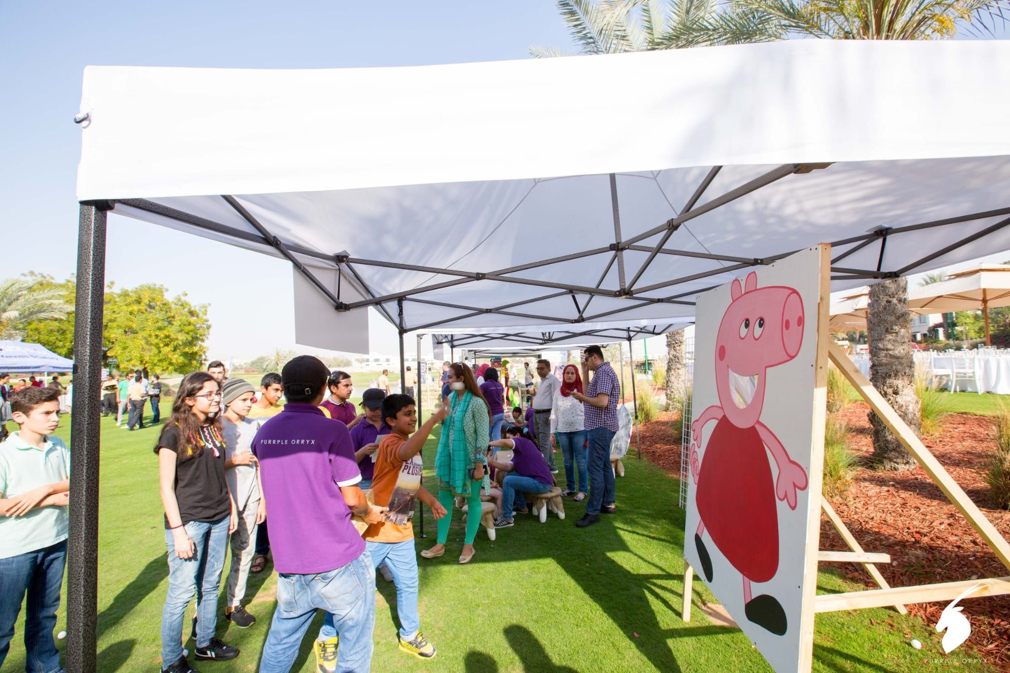 Families at a Peppa Pig themed game stall under a gazebo