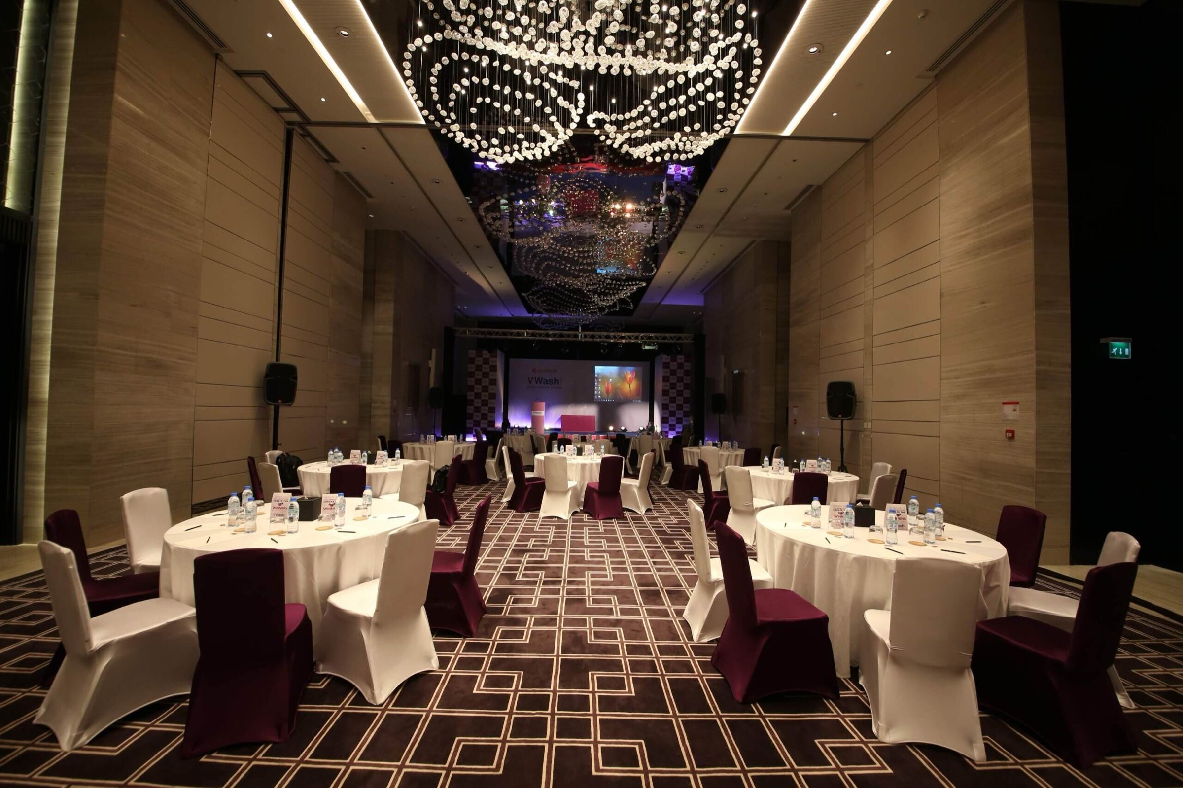Elegant dinner setup with round tables under a crystal chandelier ceiling