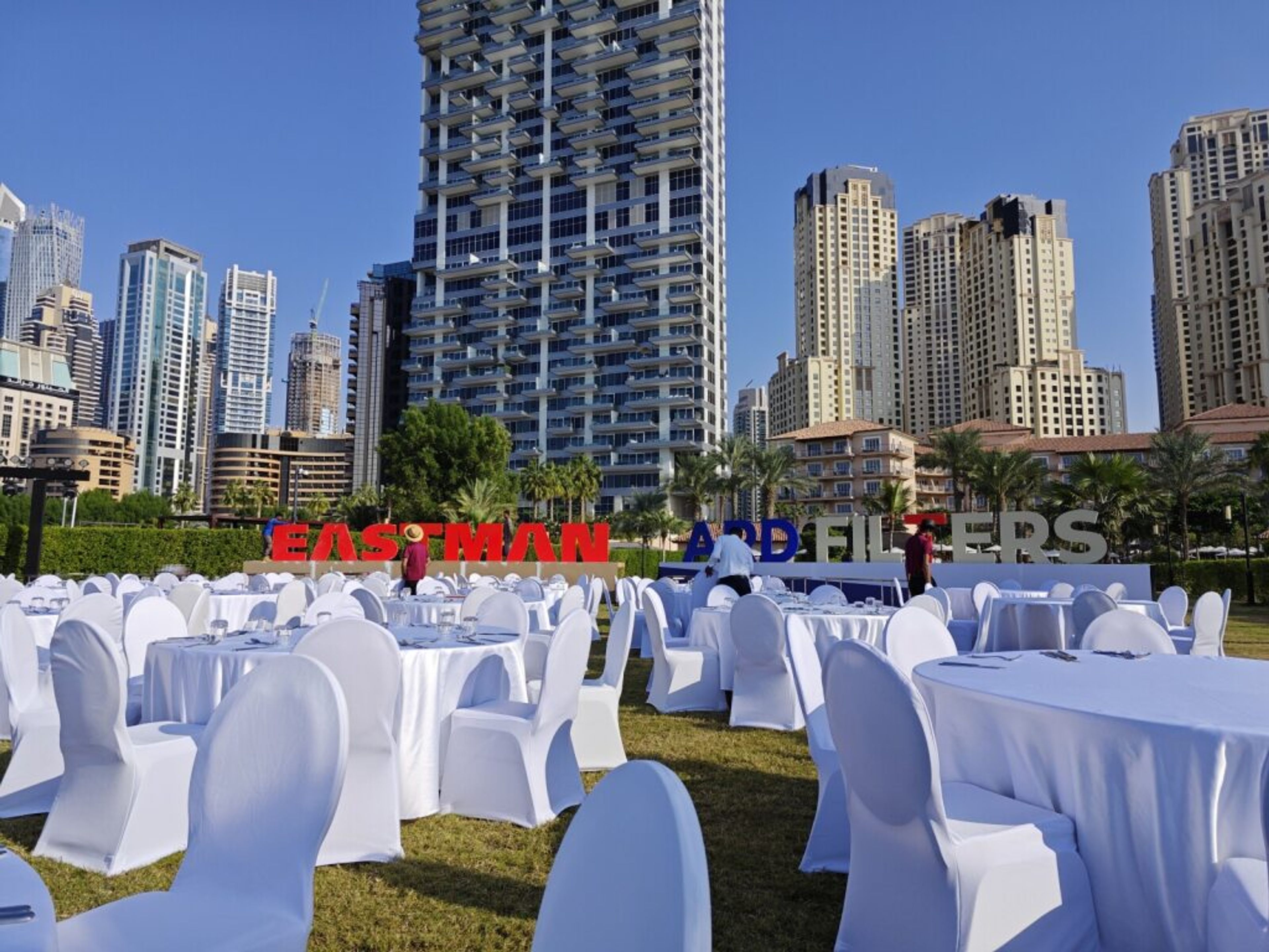 Outdoor event with white chair covers set among city towers
