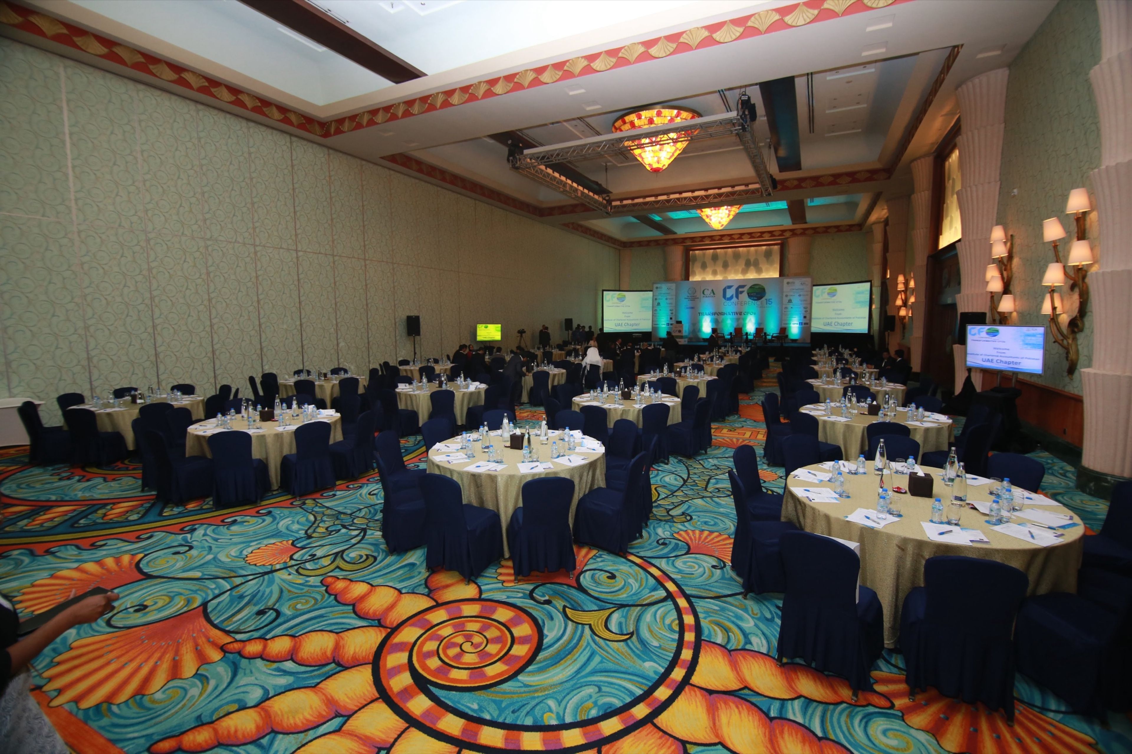 Banquet hall with round tables and navy chairs on a patterned carpet