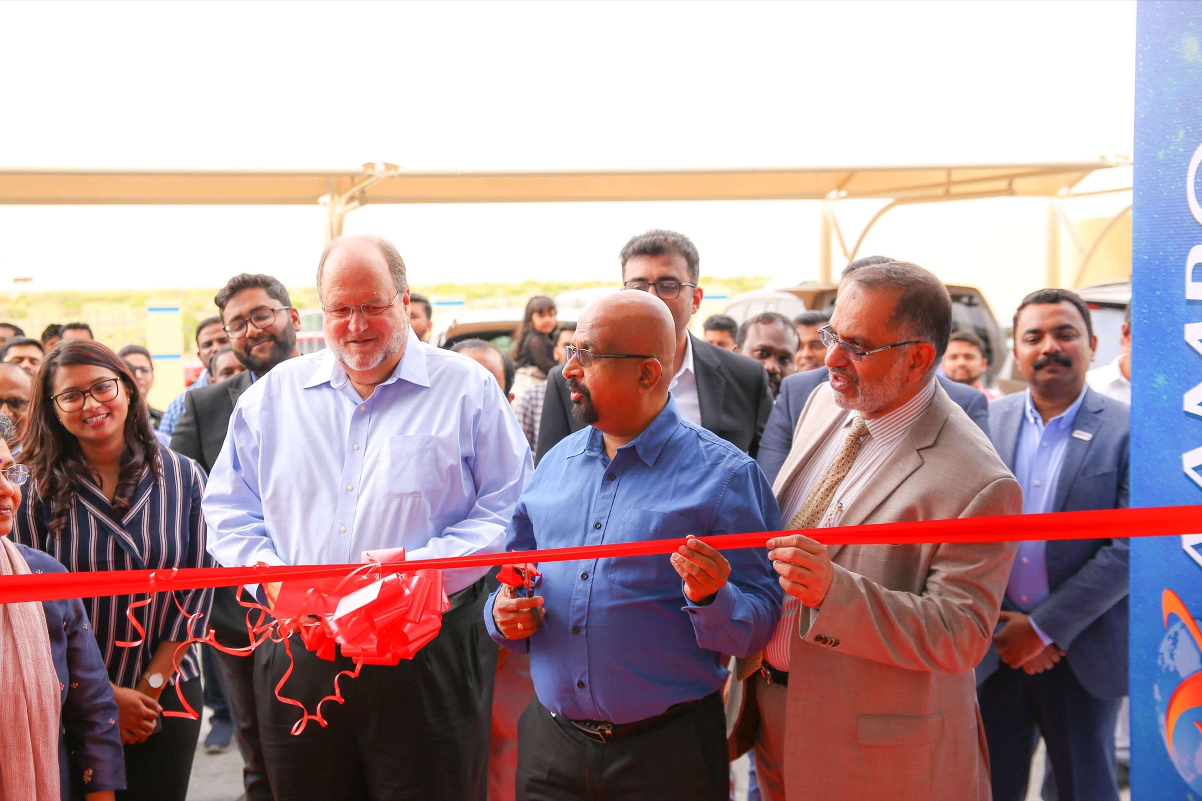 Executives cutting a red ribbon at a grand opening ceremony