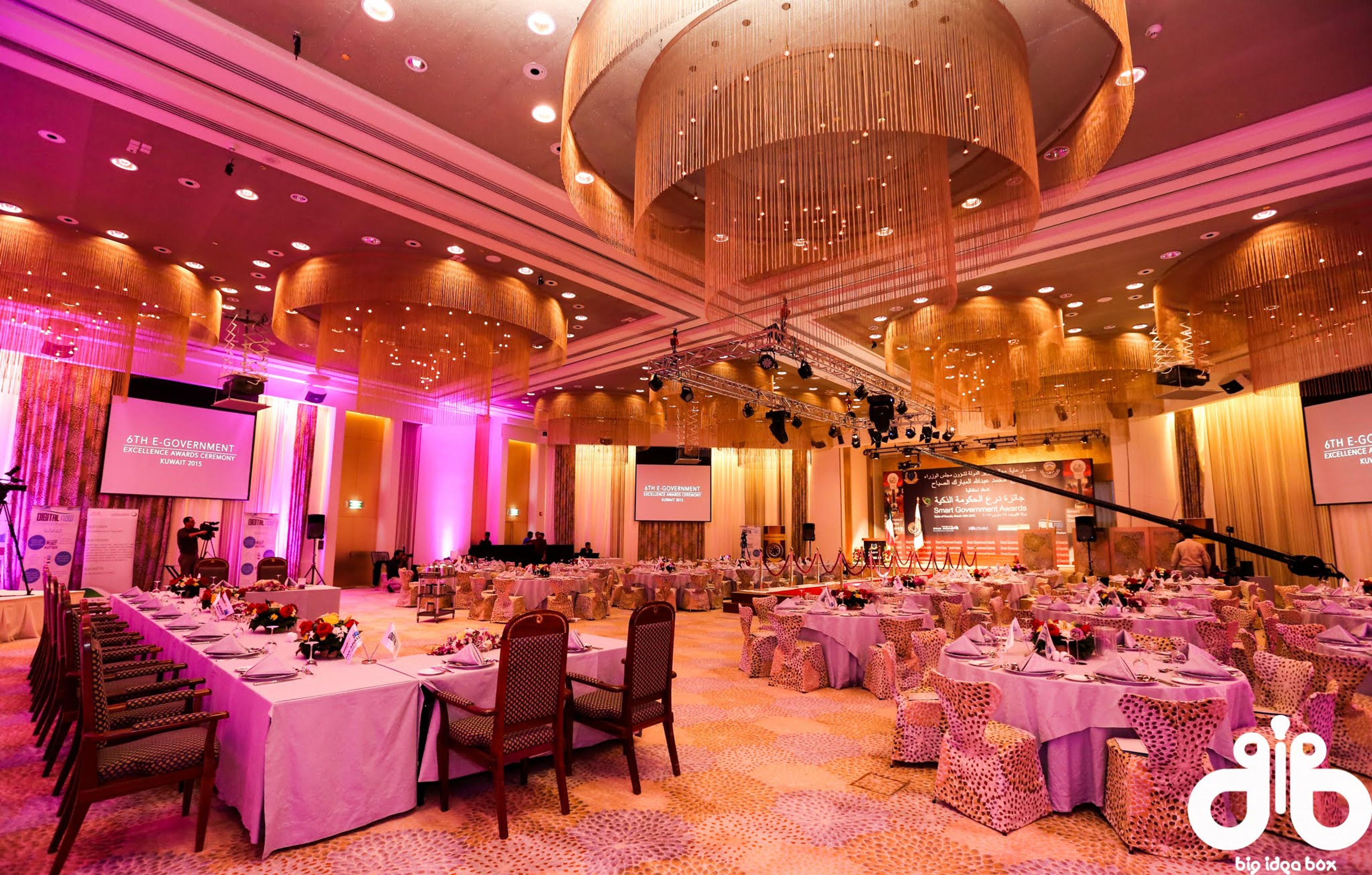 Ballroom awards dinner with pink uplighting, banquet tables and stage screens for the Tatweej Excellence Award