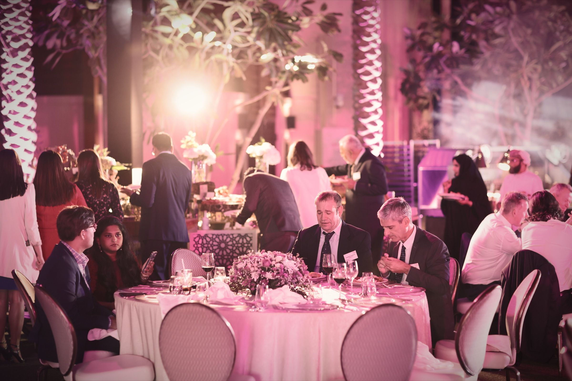 Guests dining at a gala dinner surrounded by pink floral décor