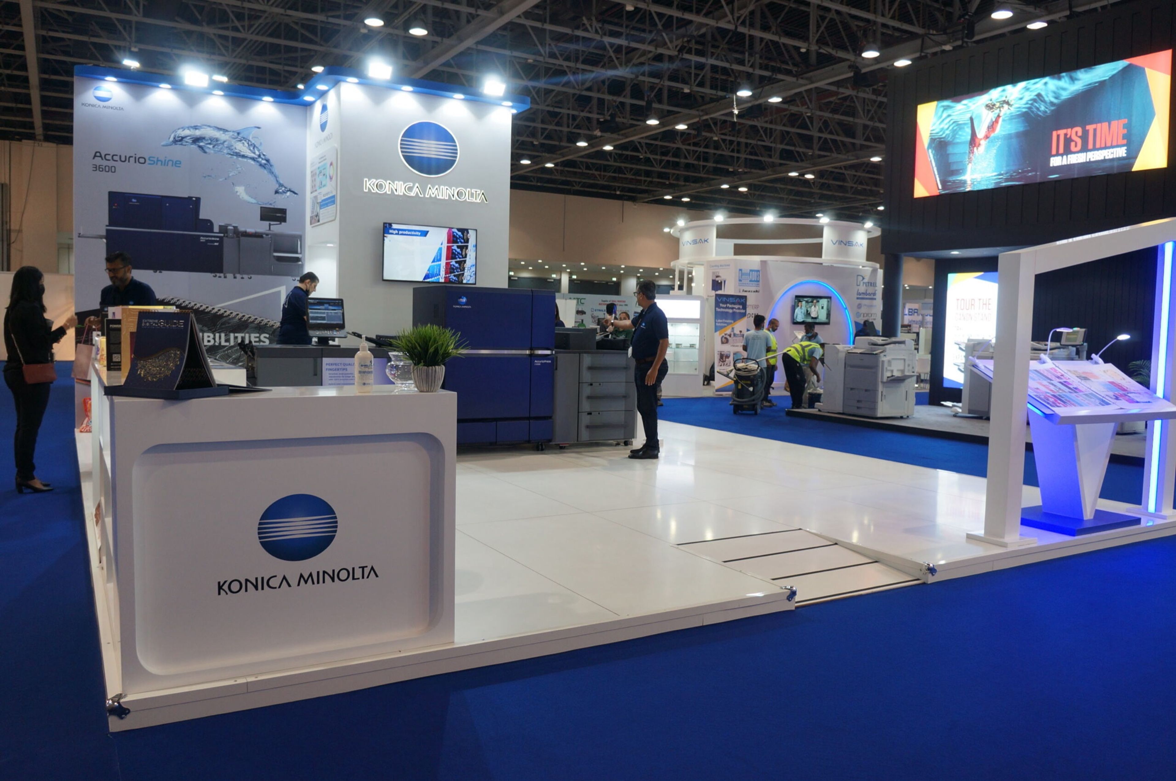 Modern exhibition stand with a white reception counter and branded screens