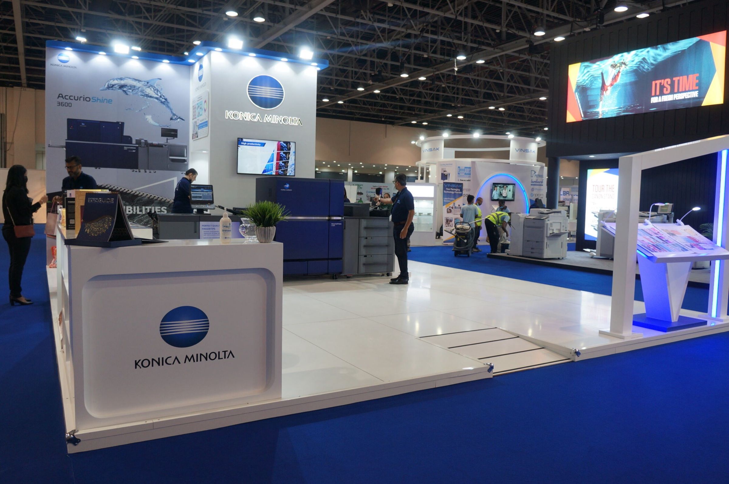 Modern exhibition stand with a white reception counter and branded screens