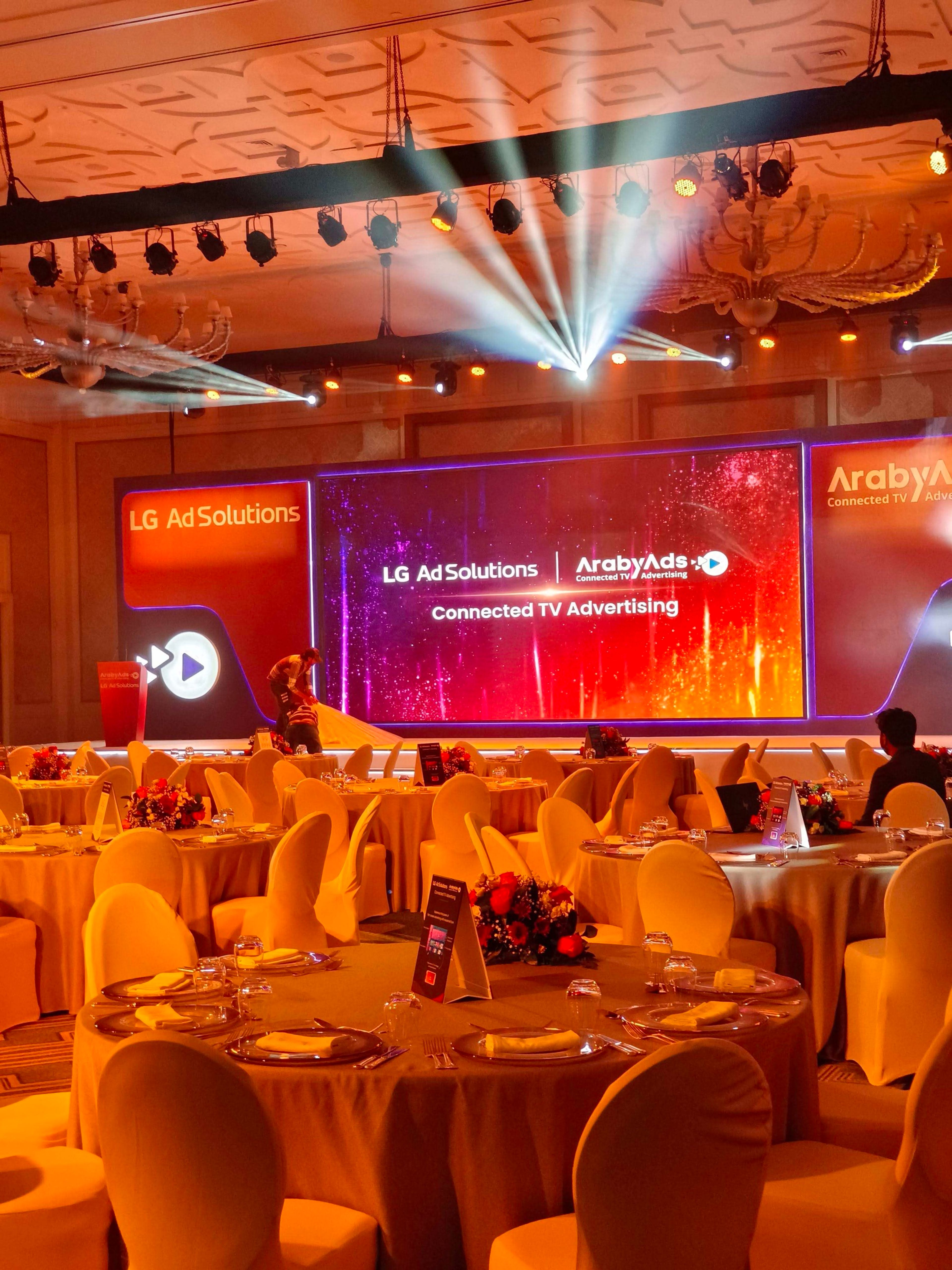 Stage lighting beams over a ballroom during a corporate event setup