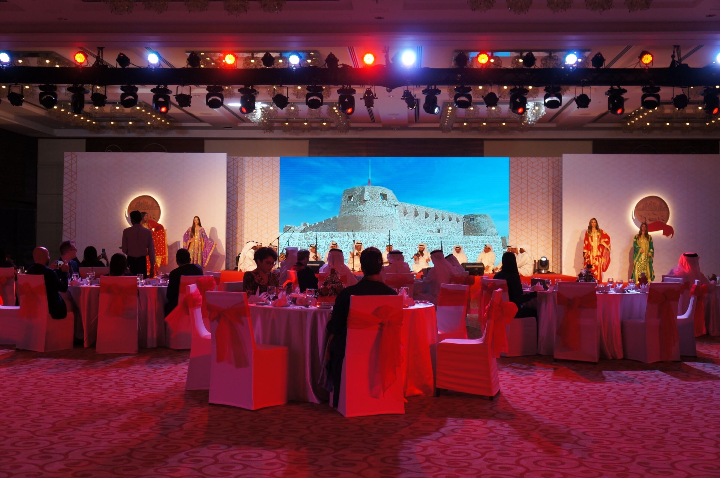 Banquet hall with round tables facing a stage screen