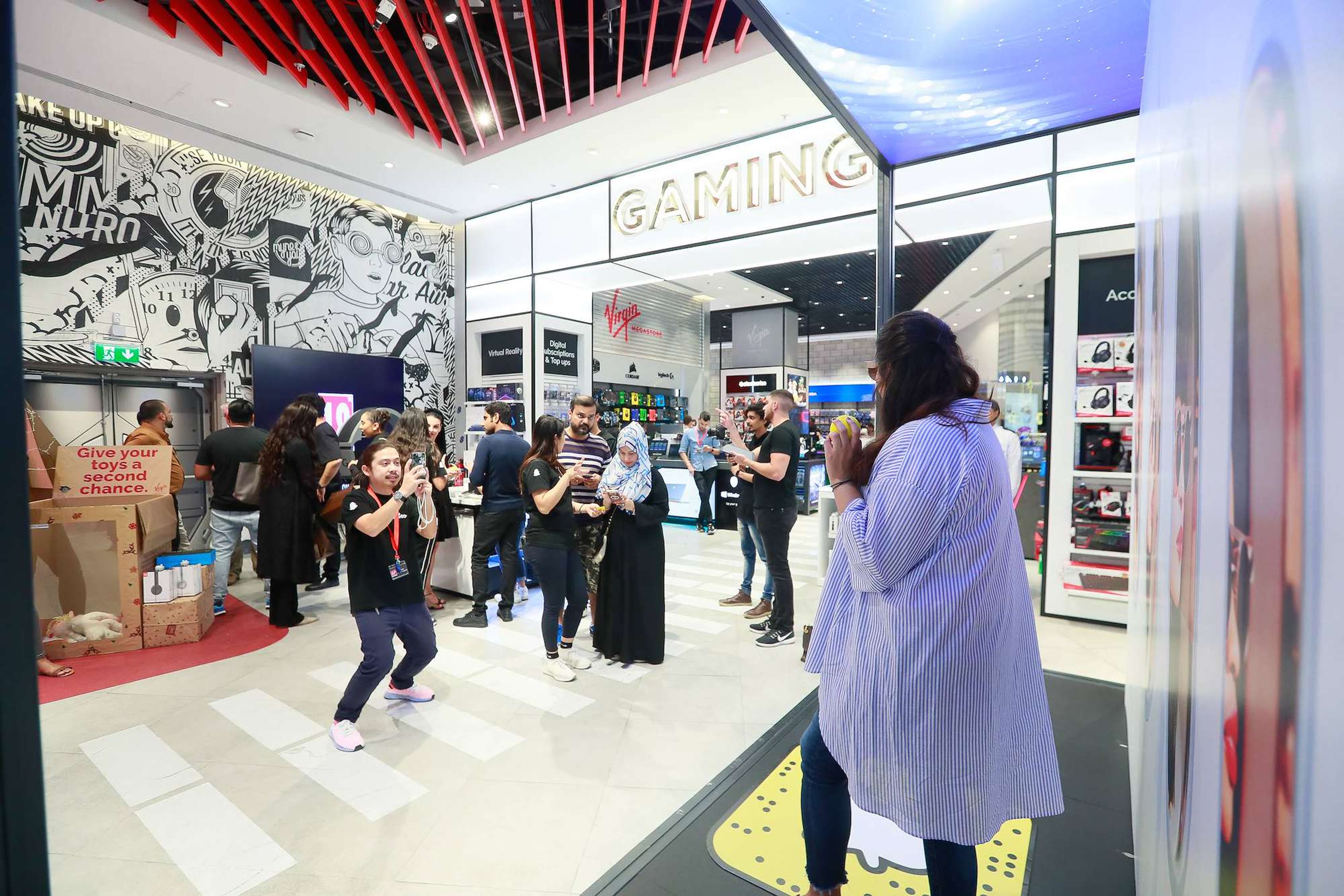 Shoppers trying an interactive brand activation inside a Dubai mall with brand ambassadors helping