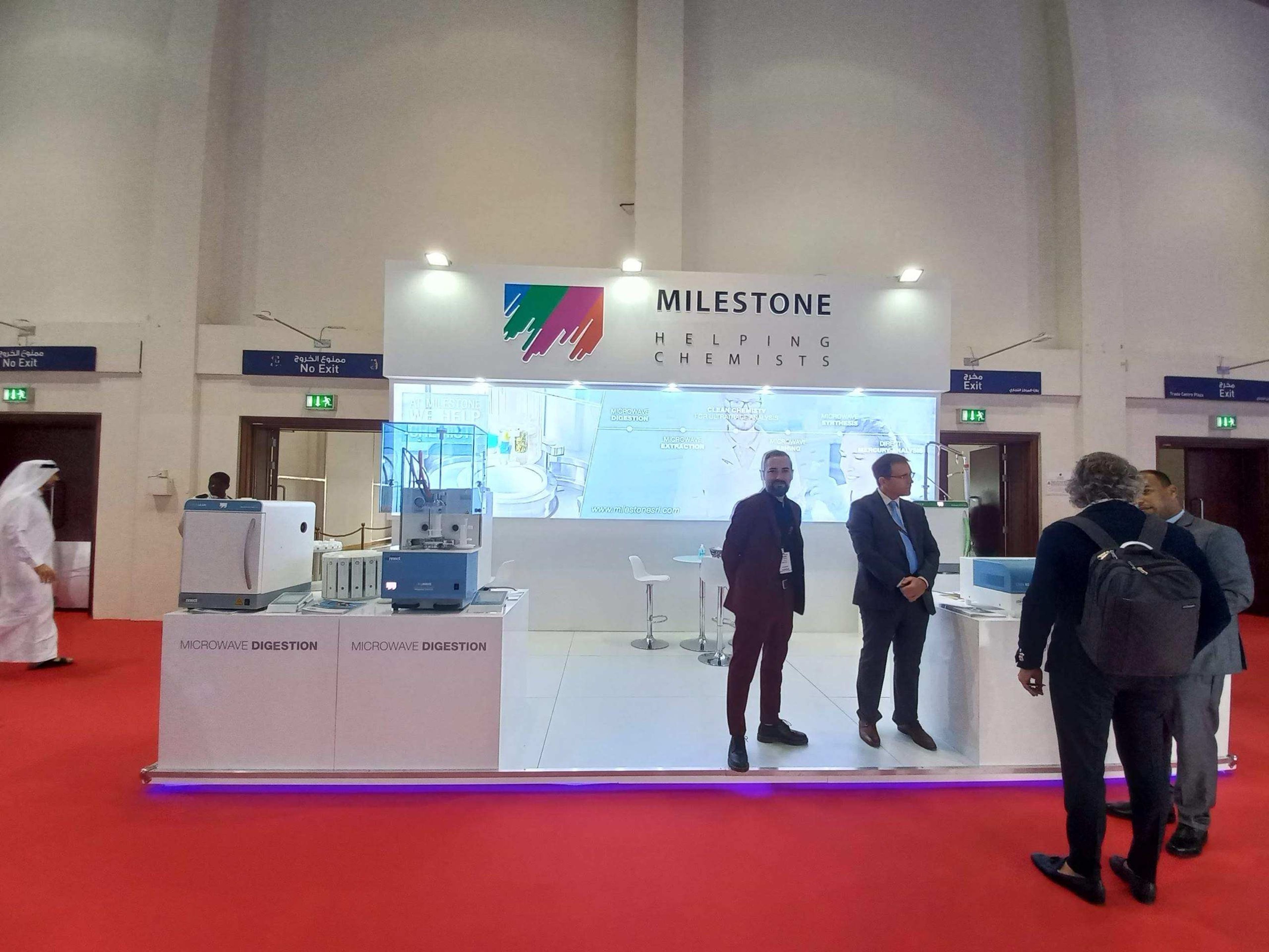 Exhibition stand with a white counter and visitors in conversation