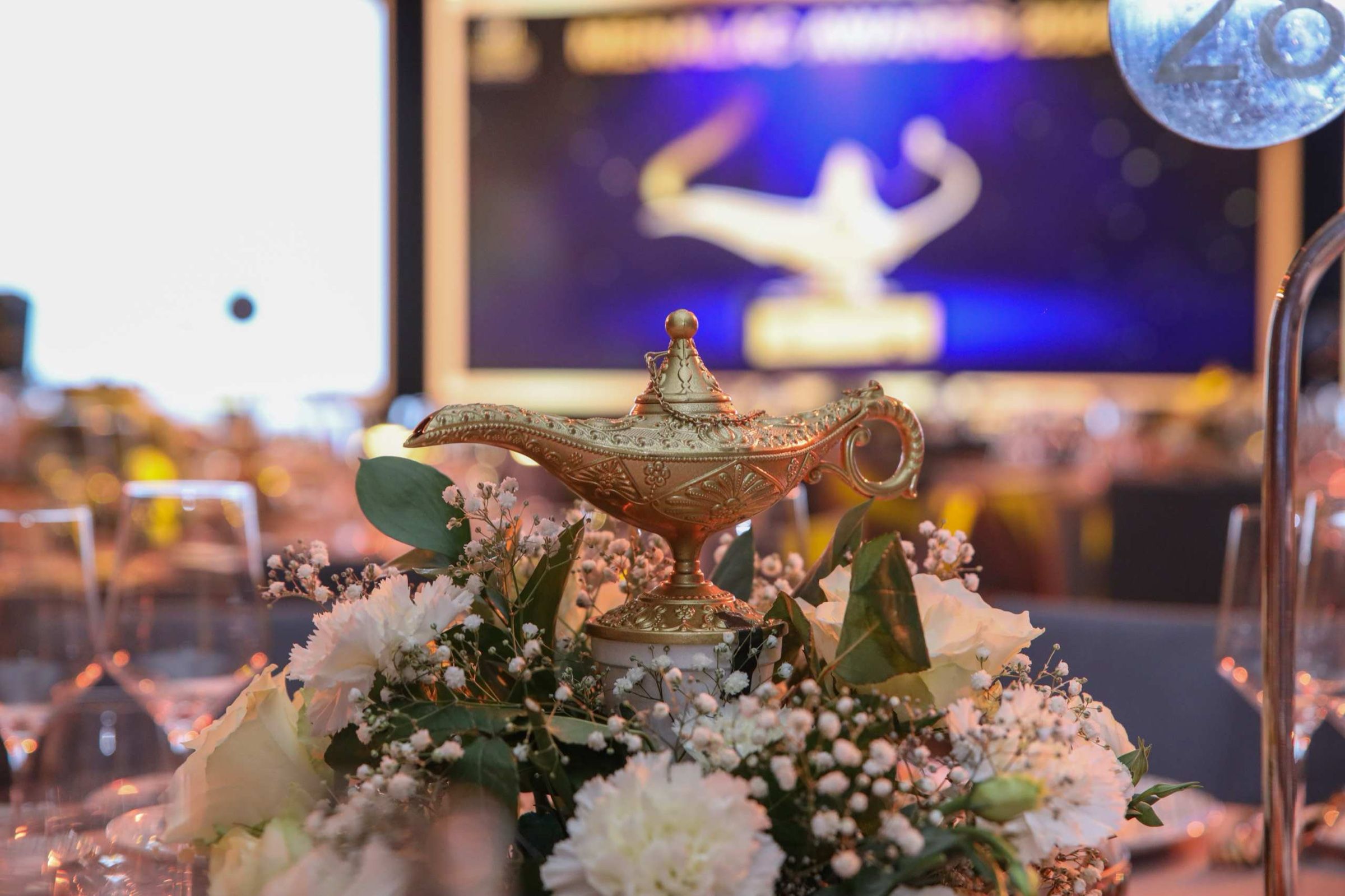 Table centrepiece with a stage performer in the background at a gala dinner