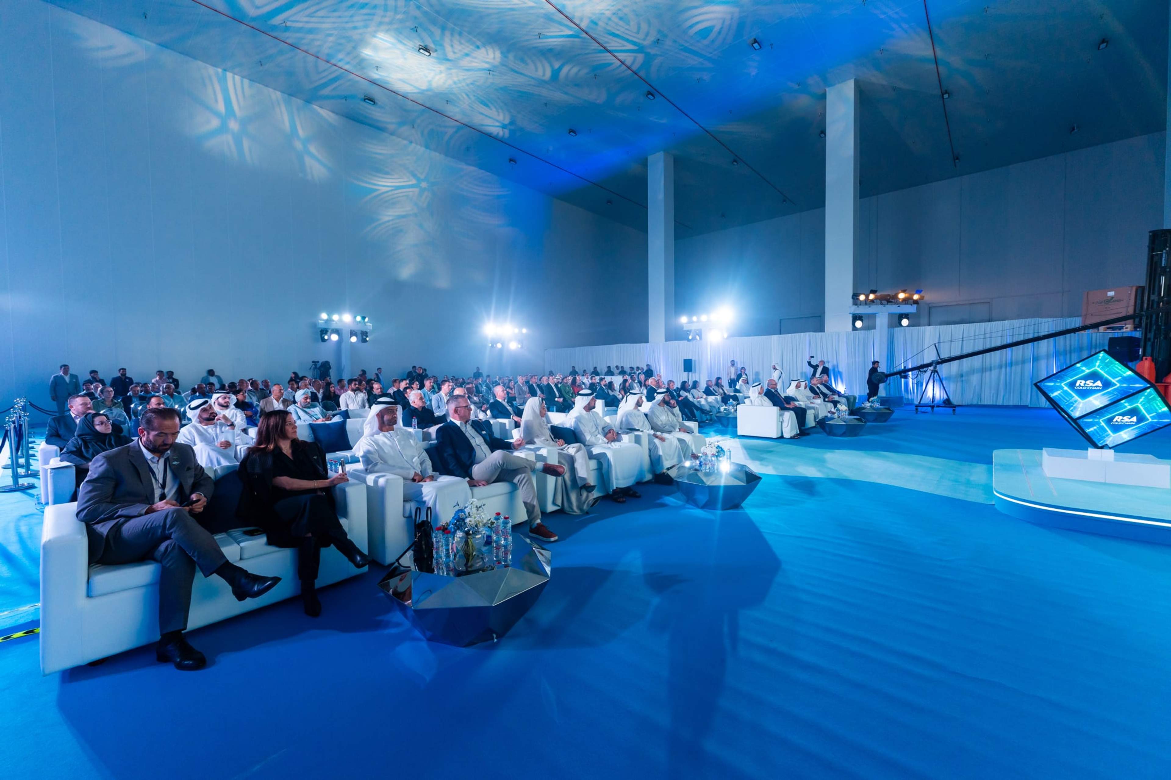 The same launch hall full of guests on white lounge seating under blue light