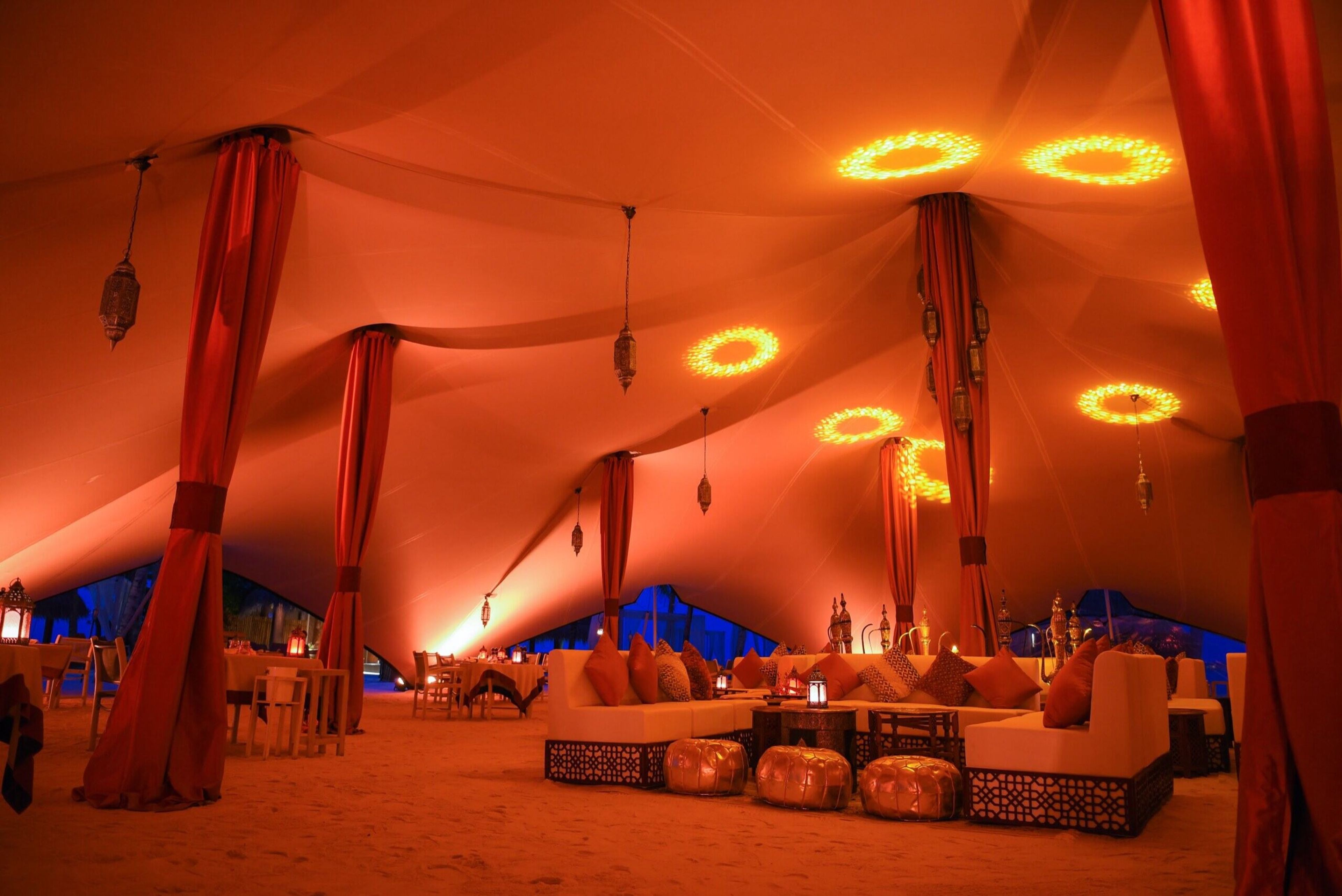 Tent interior with warm orange lighting and lounge seating