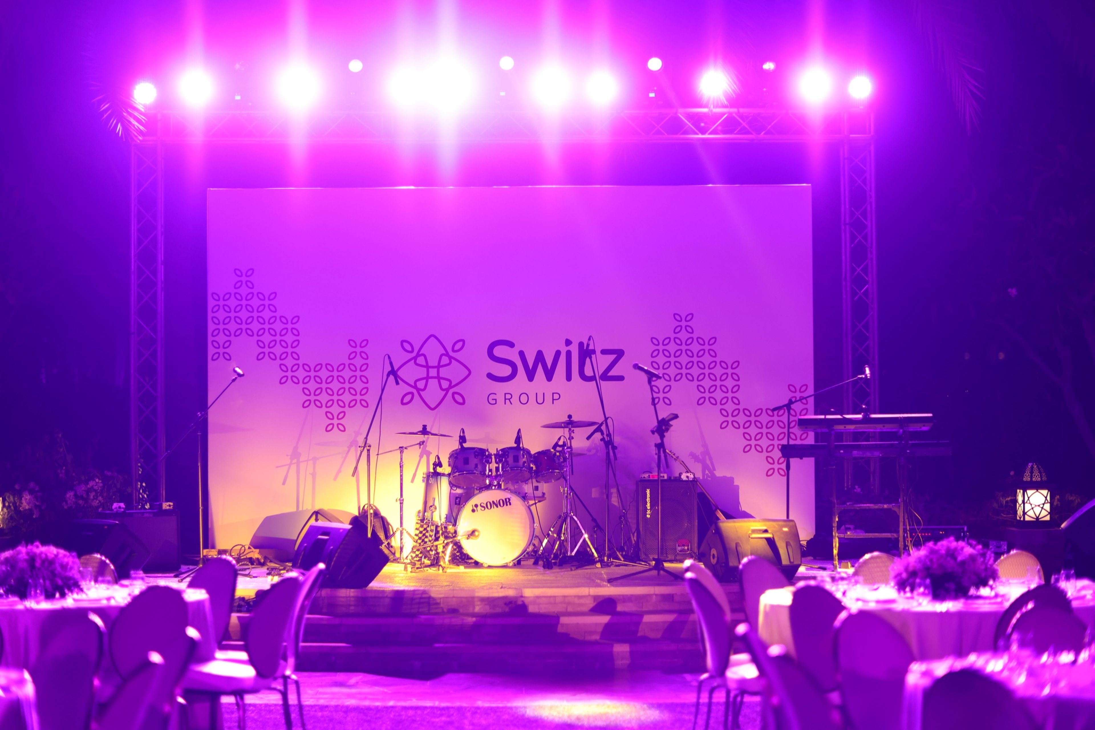 Purple-lit stage with a band setup and branded backdrop